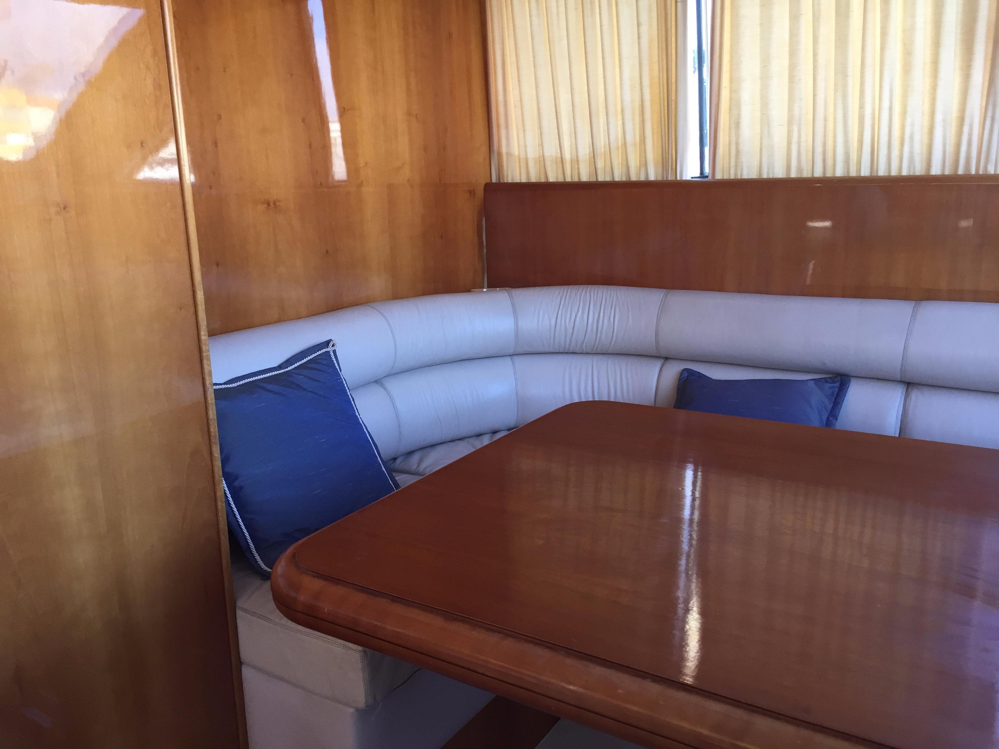 Luxurious interior of 1994 Falcon 76 yacht with wooden table and cushioned seating.