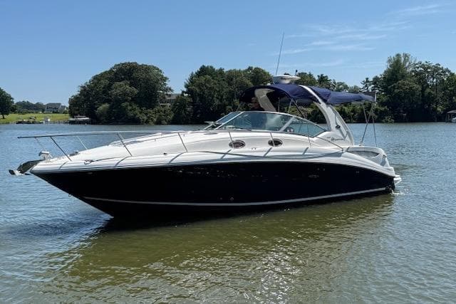 2006 Sea Ray Sundancer 320 boat on calm water, featuring sleek design and blue canopy.