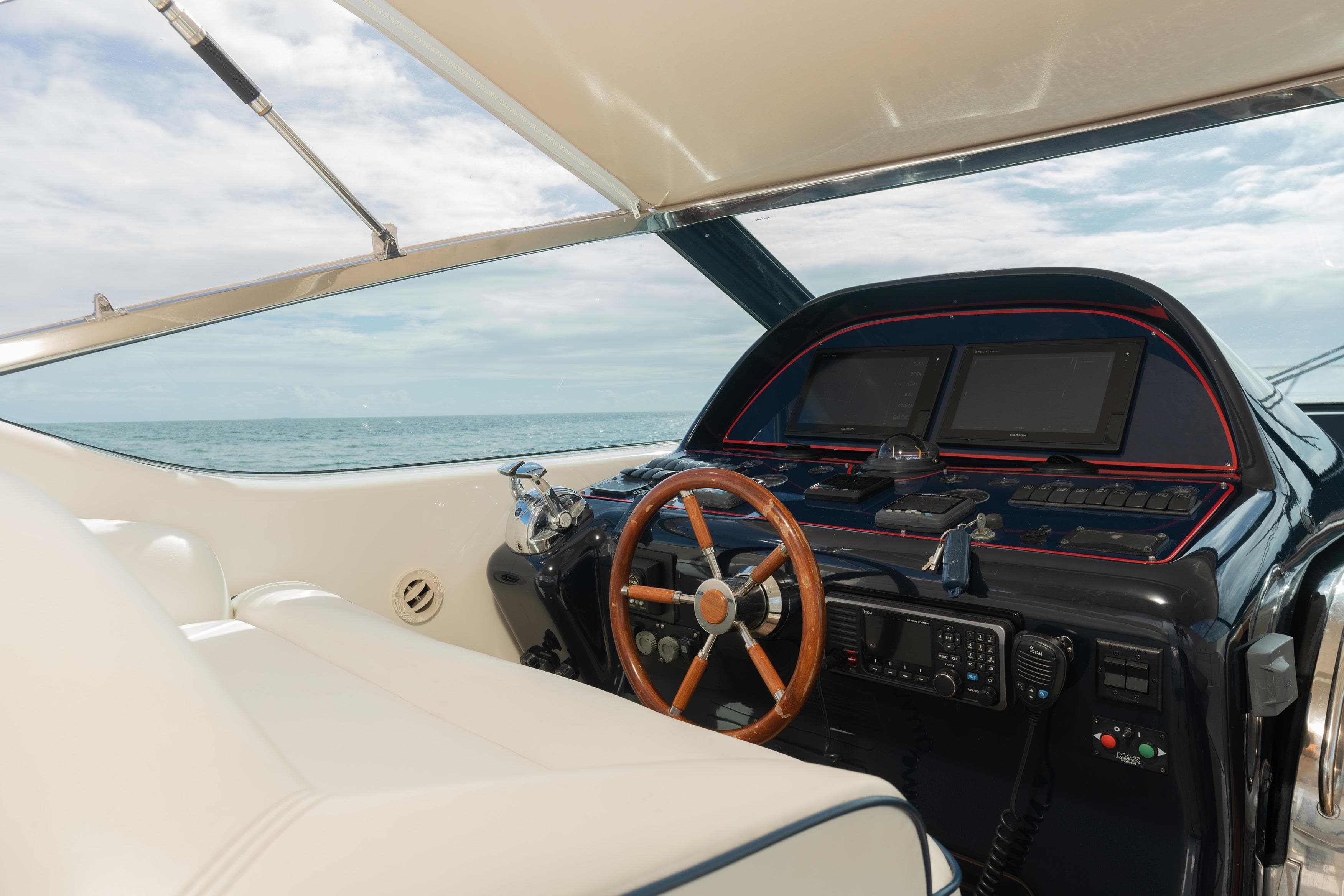 Uniesse 48 Open 2001 yacht helm with wooden steering wheel and navigation equipment.