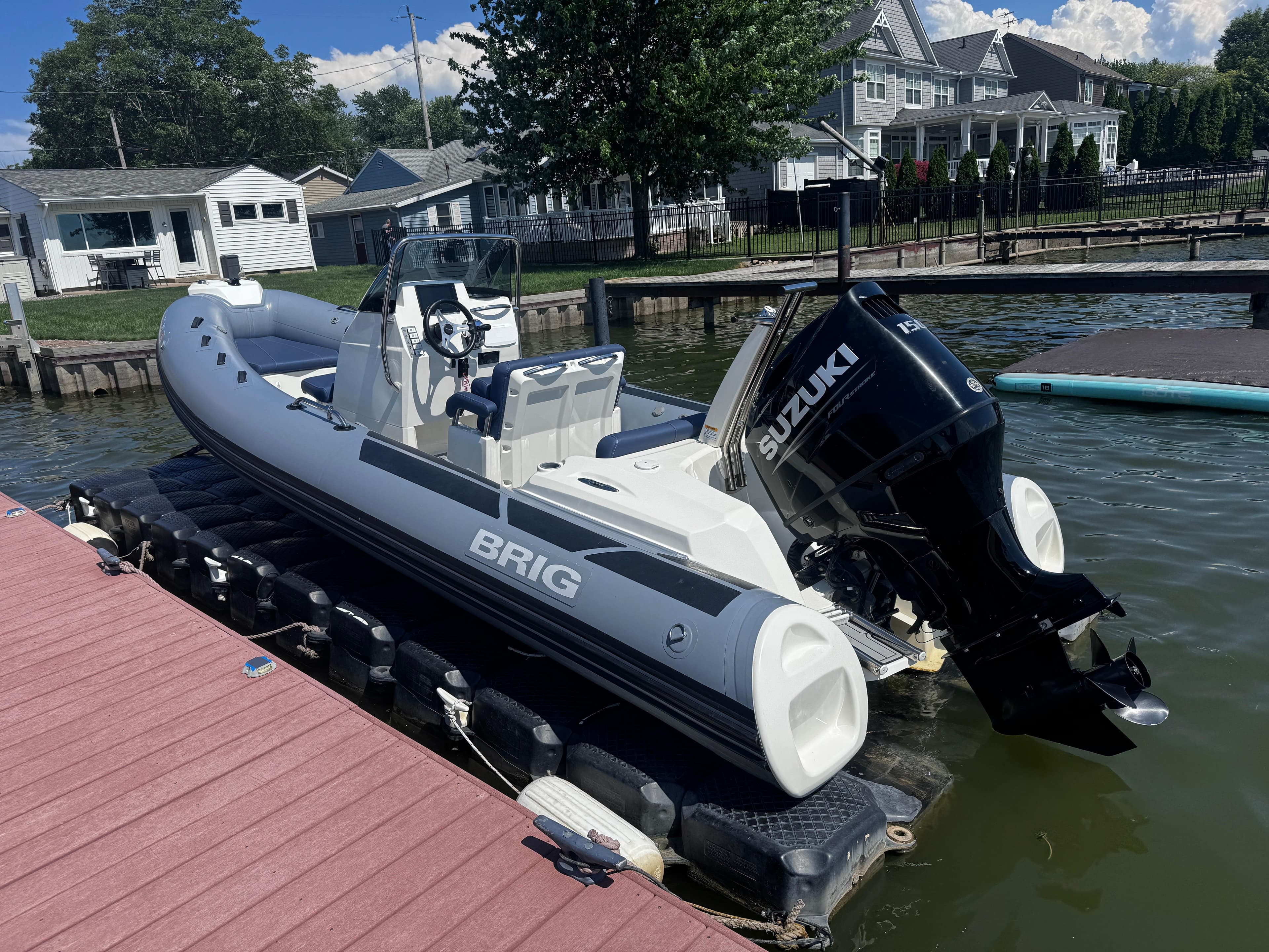 2022 Brig Eagle 6 boat with Suzuki engine docked by waterfront homes.