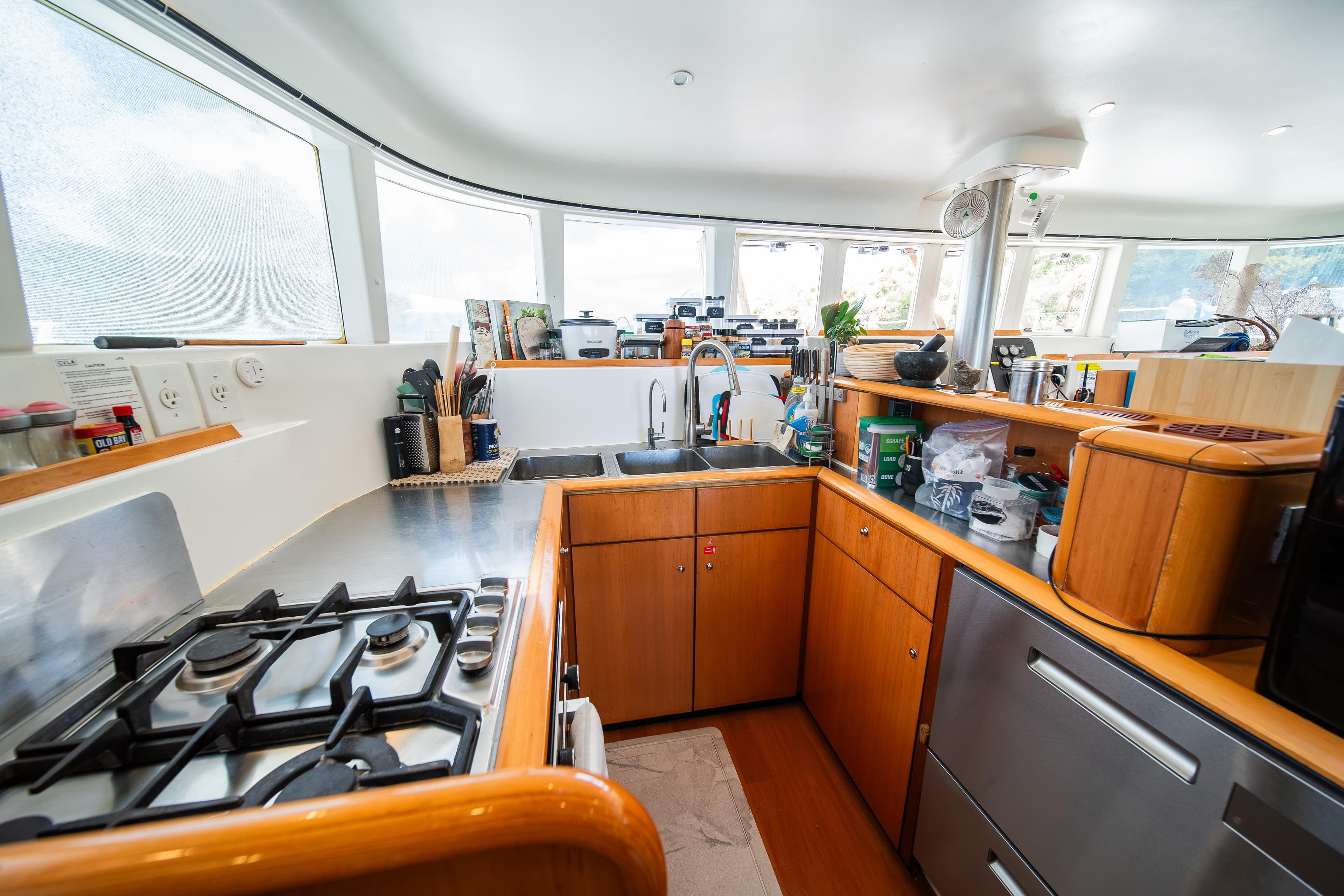 Modern kitchen interior on a 2007 Lagoon 500 yacht, featuring wooden cabinetry and stainless steel appliances.