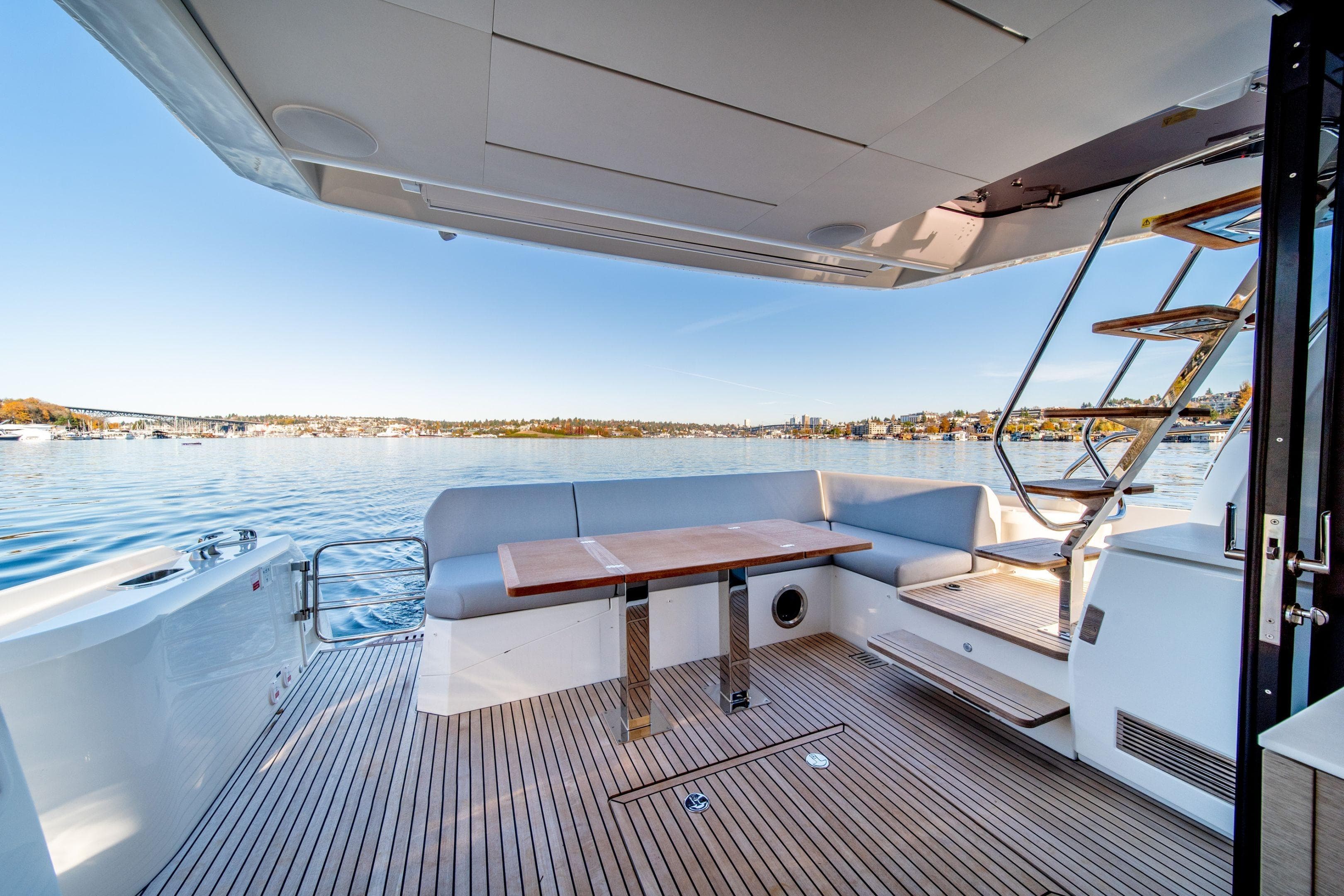 Luxurious 2026 Prestige 520 yacht deck with seating, table, and scenic waterfront view.