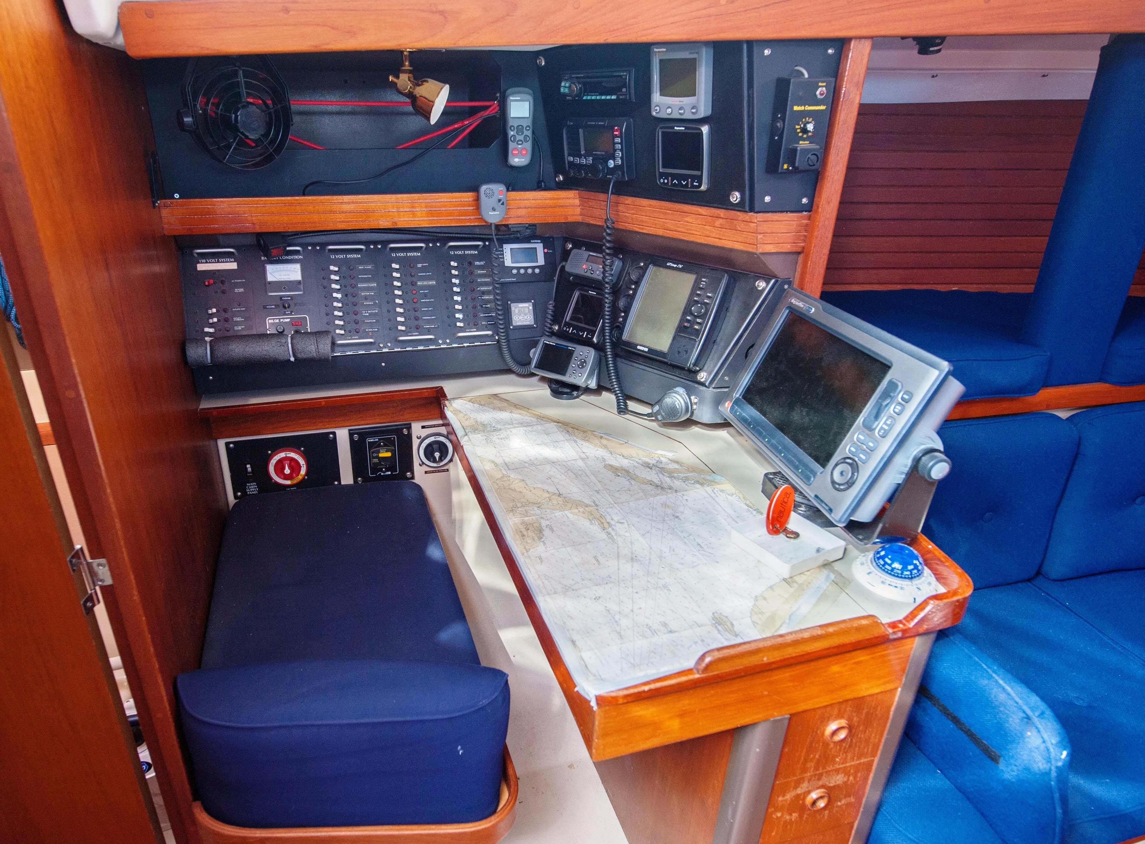 Navigation station on 1985 C&C 44 sailboat with electronic equipment and seating.