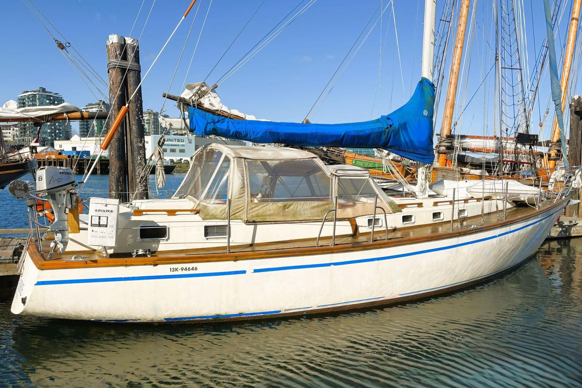 Vintage 1980 Discovery 42 sailboat docked at marina, featuring blue sail cover.