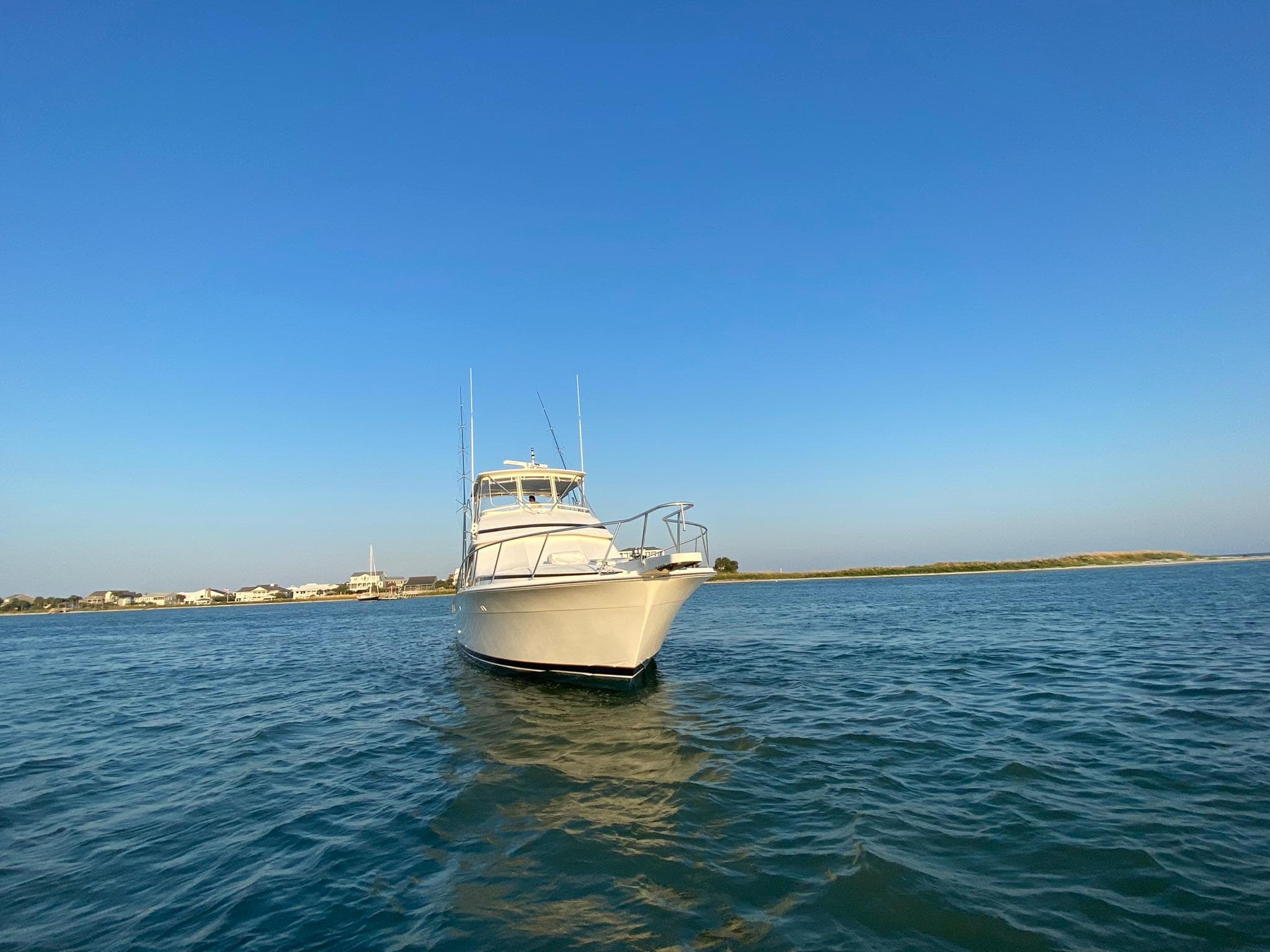 1999 Bertram 60 Convertible yacht on calm waters under clear blue sky.