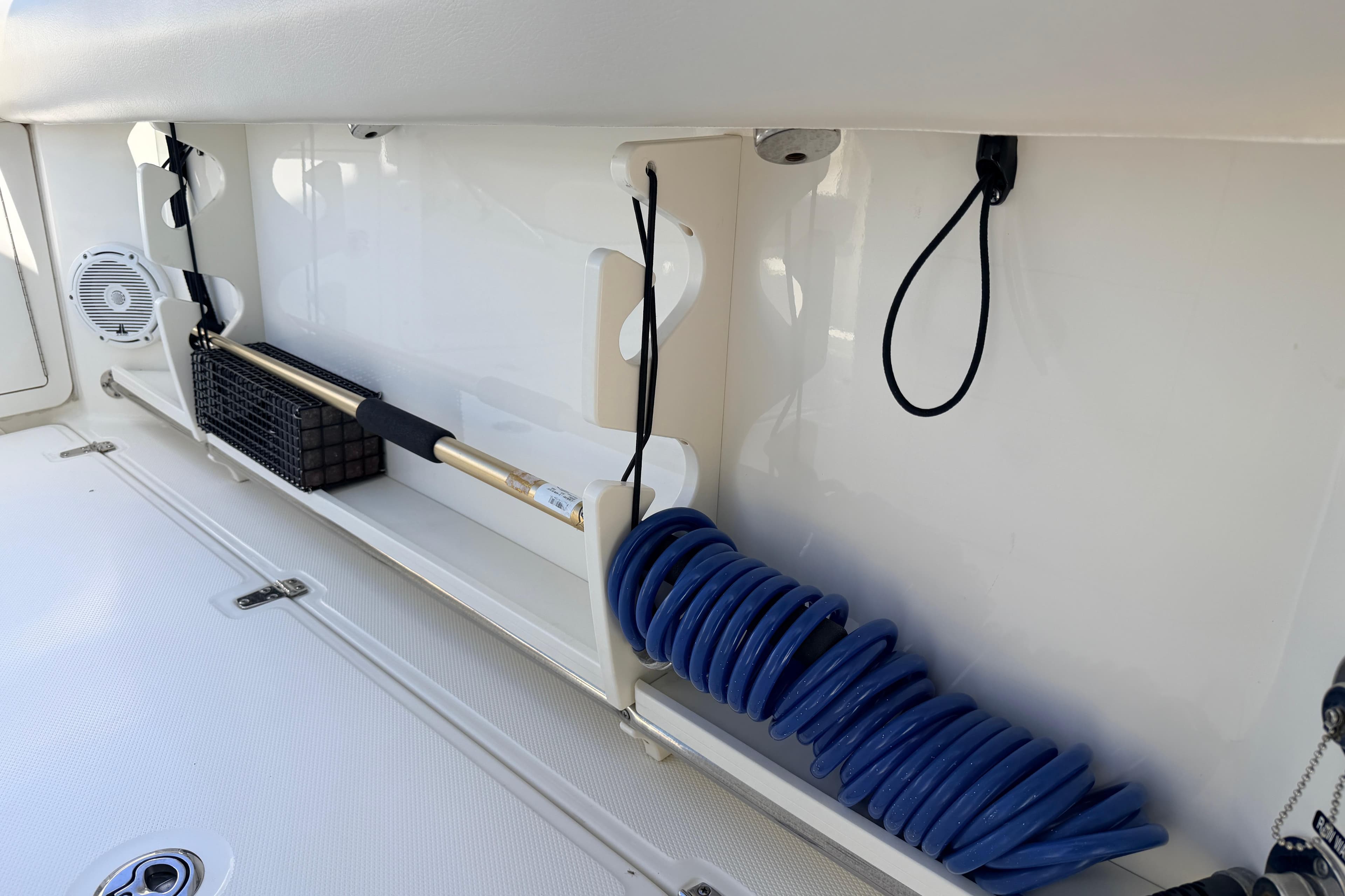Storage compartment on a 2022 Boston Whaler 250 Outrage, featuring a coiled blue hose and accessories.