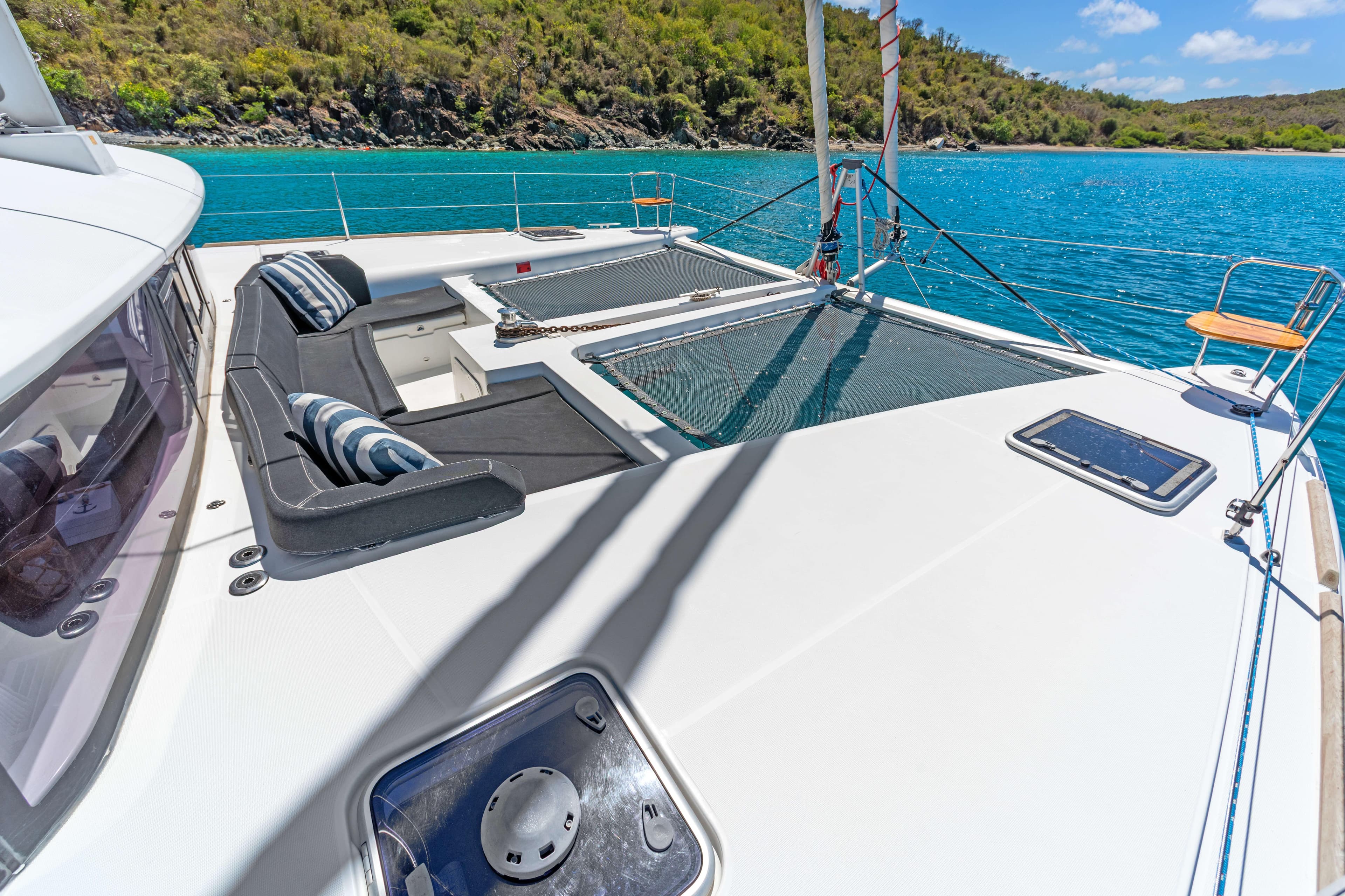 Luxurious Lagoon 450 F catamaran deck with seating, overlooking turquoise waters and lush coastline.