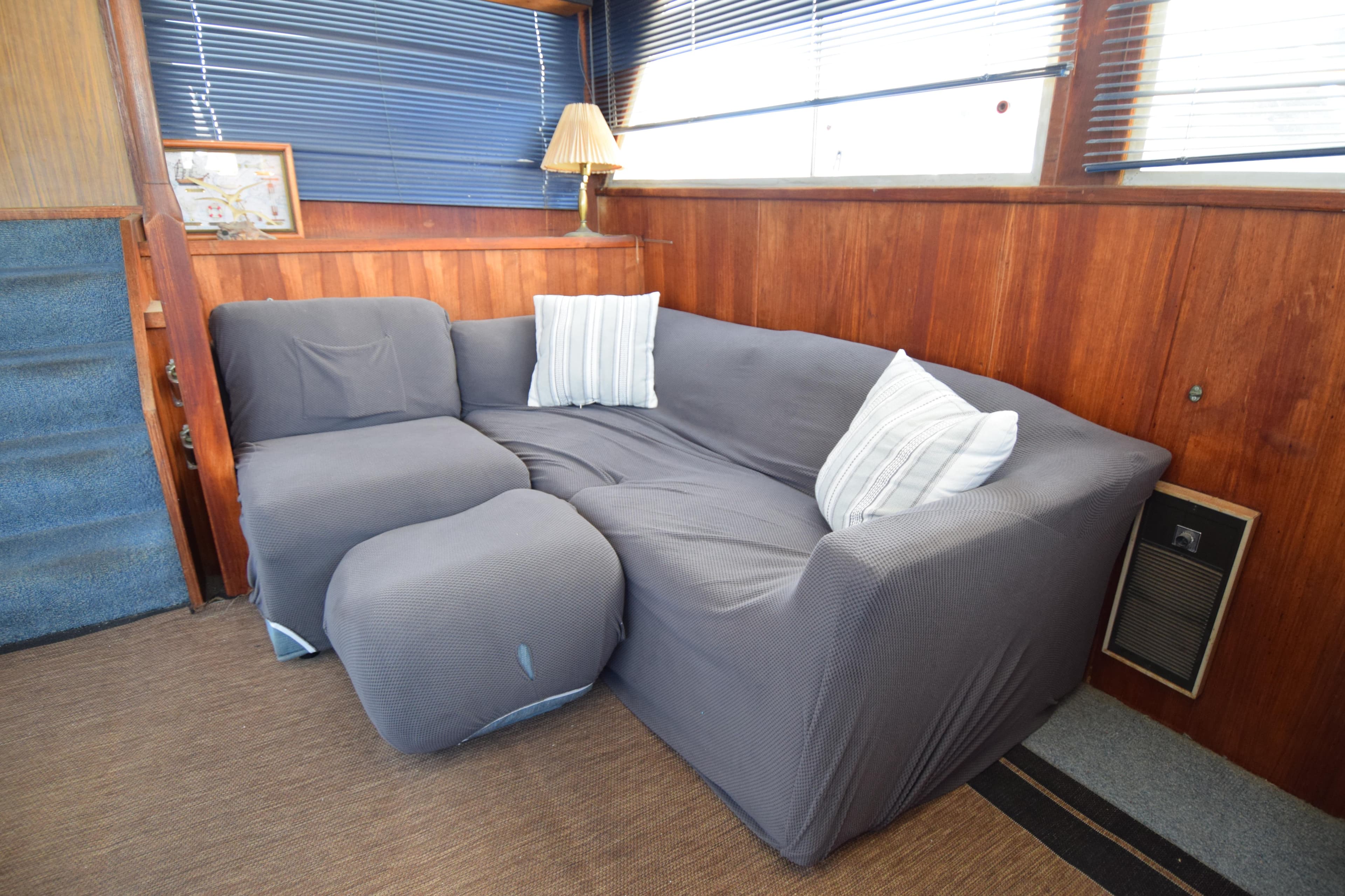 Cozy seating area in 1977 Uniflite 42 Double Cabin with gray sofa and striped pillows.