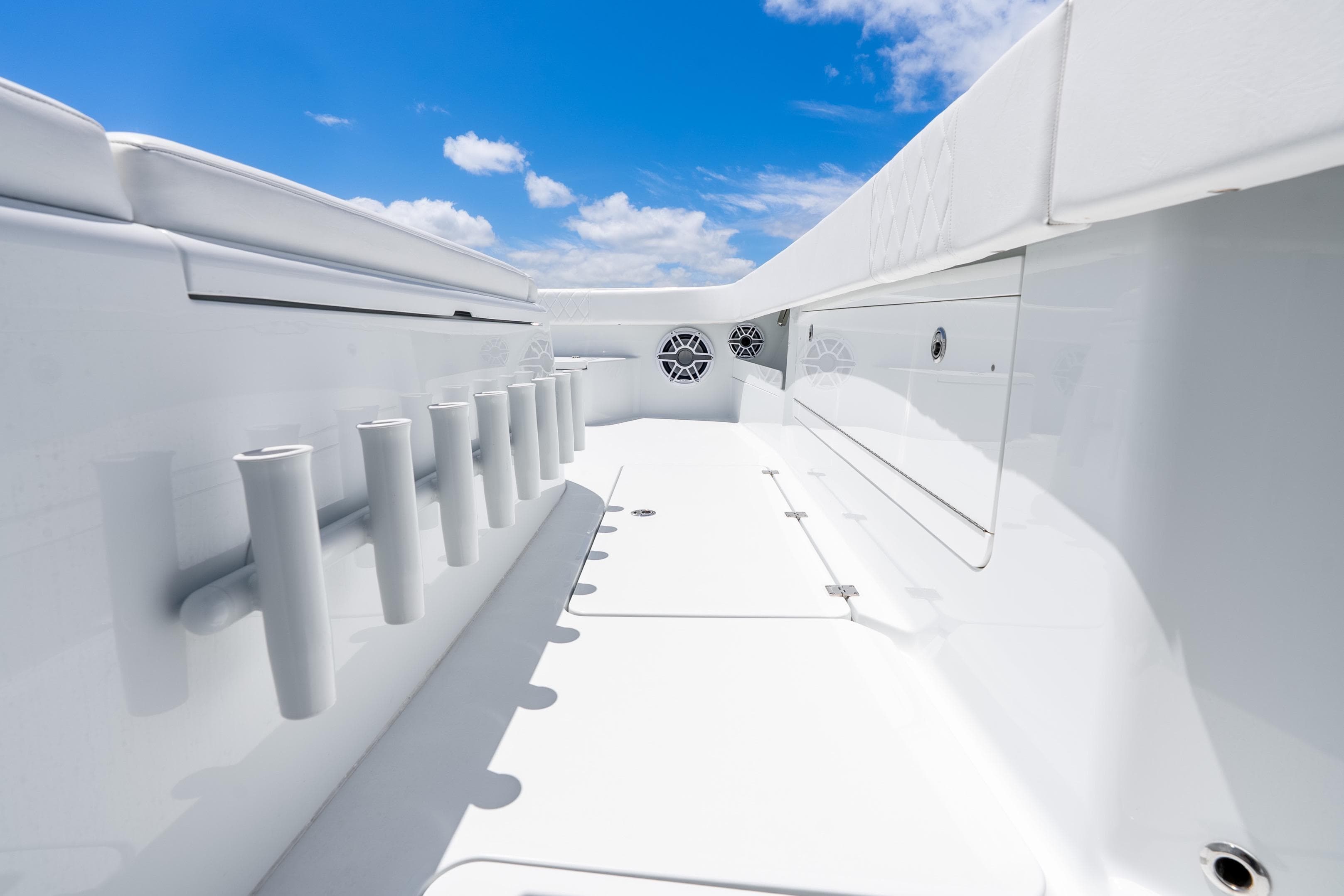 2025 Freeman 43 boat deck with rod holders and storage, under a clear blue sky.