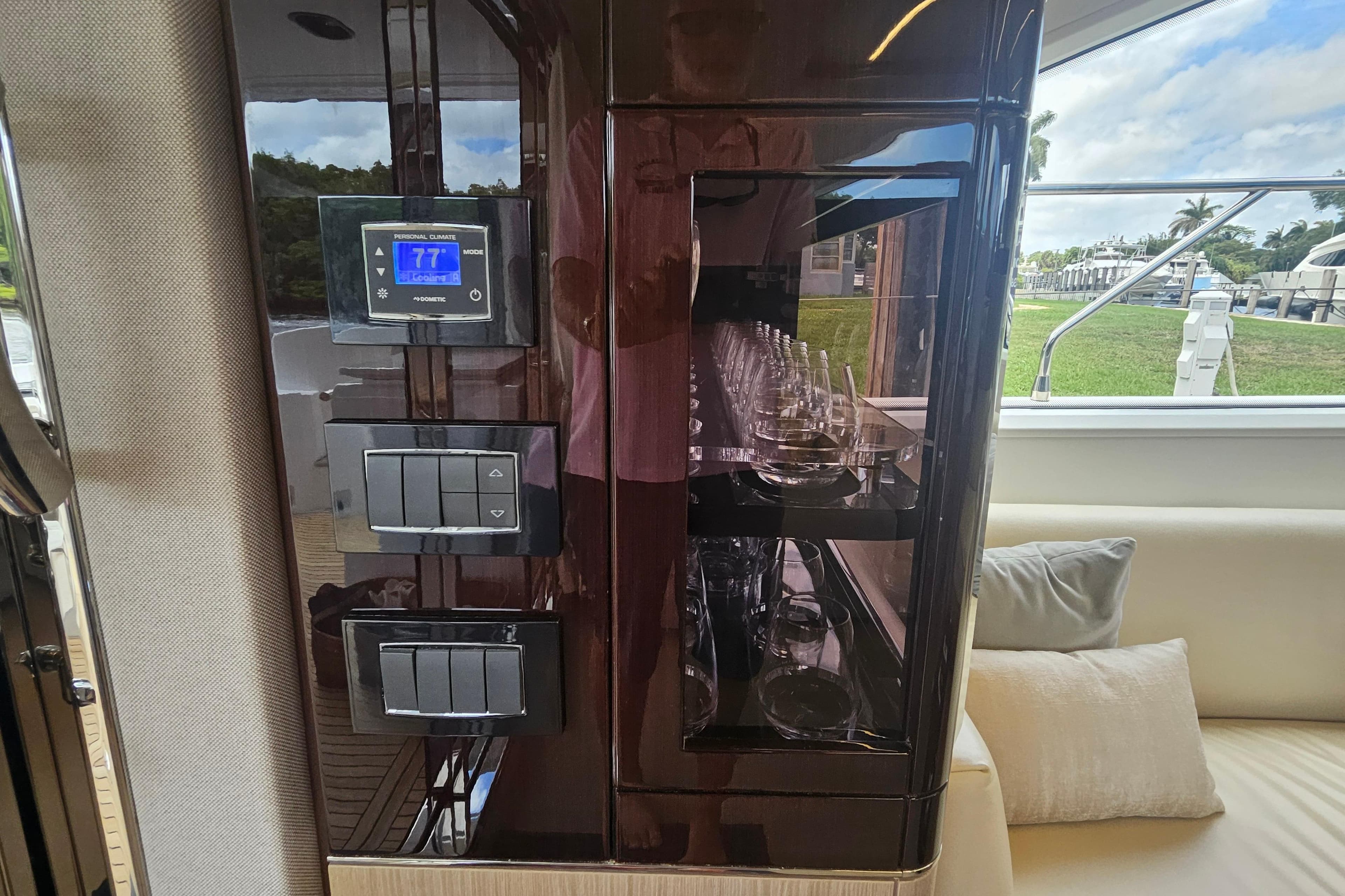 Luxurious interior of 2022 Azimut 66 yacht featuring control panel and glassware display.