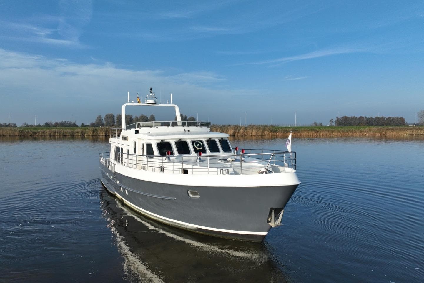 2021 Altena Trawler 50 with stabilizers cruising on a calm river under a clear blue sky.