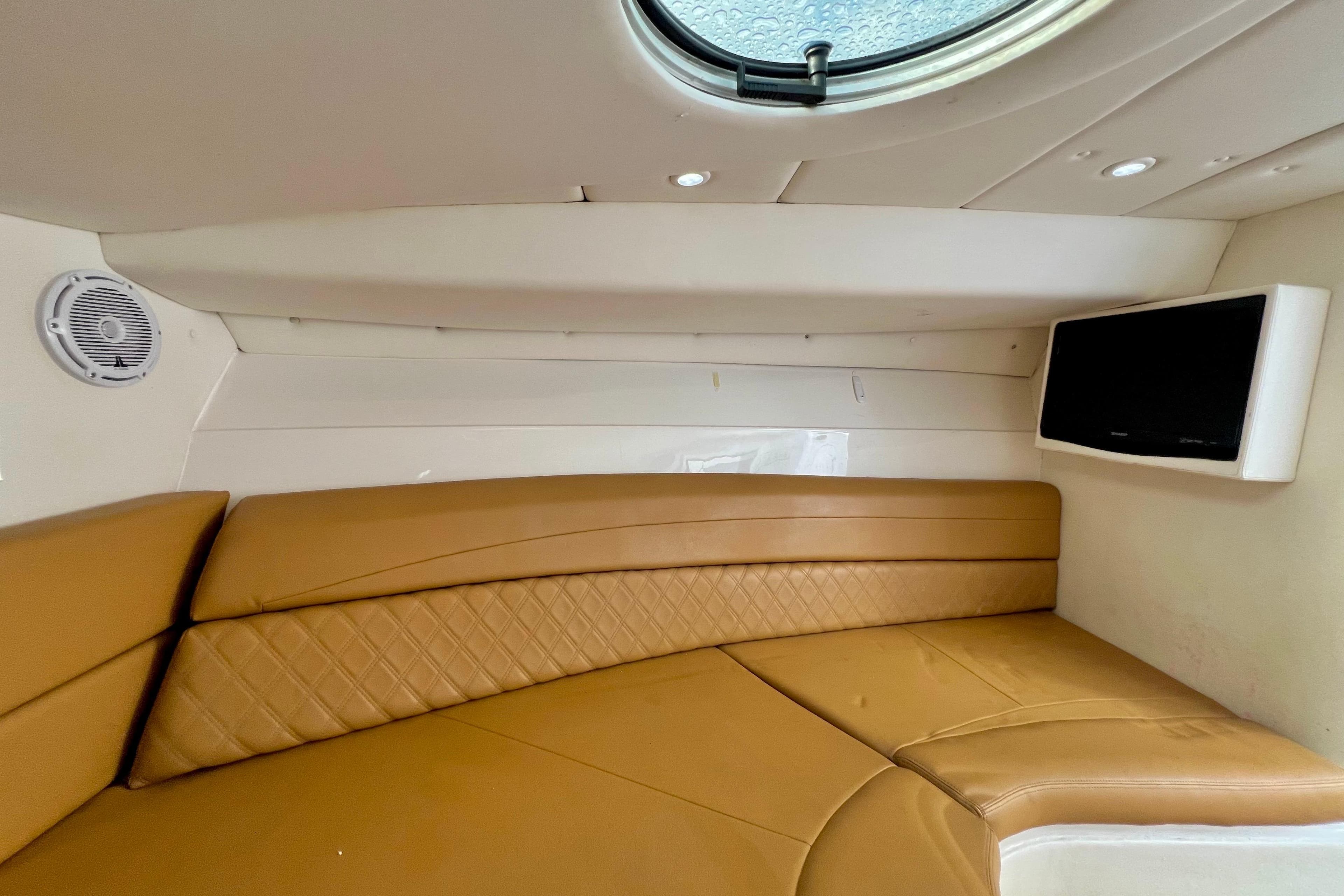 Interior of 2011 Deep Impact 36 Open boat with tan seating and wall-mounted TV.
