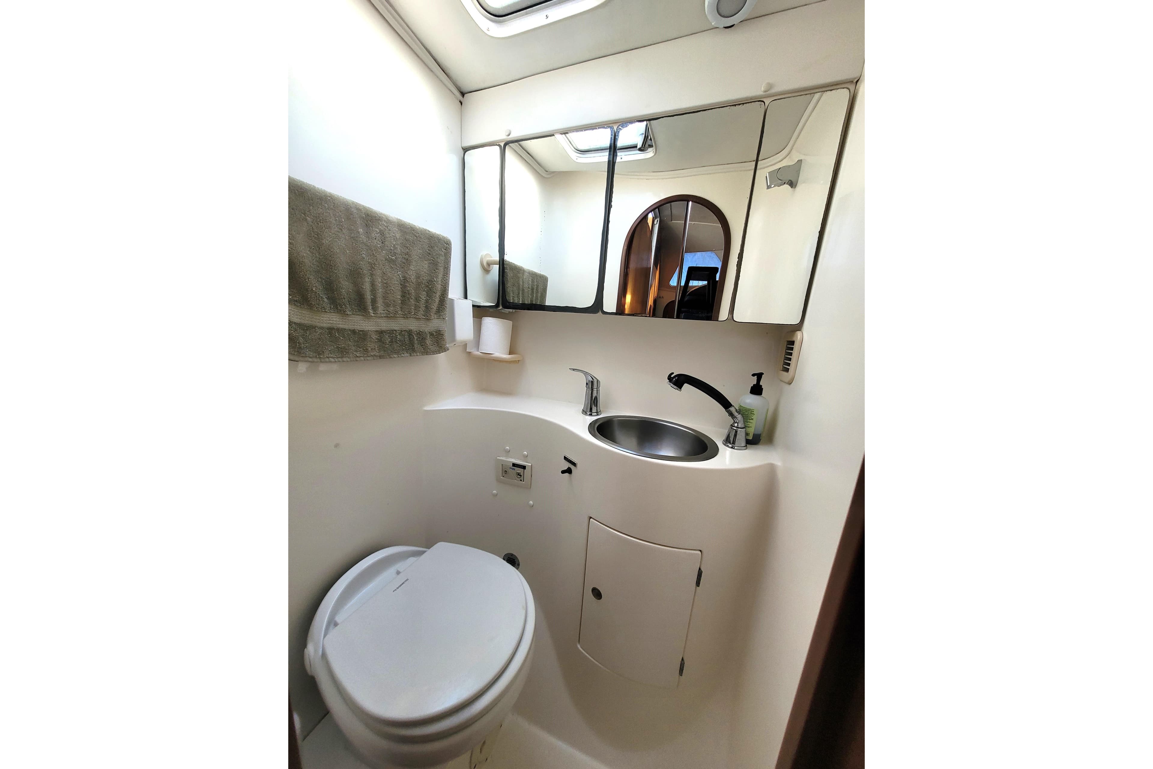 Compact bathroom in a 1995 Lagoon TPI boat with toilet, sink, and mirror.