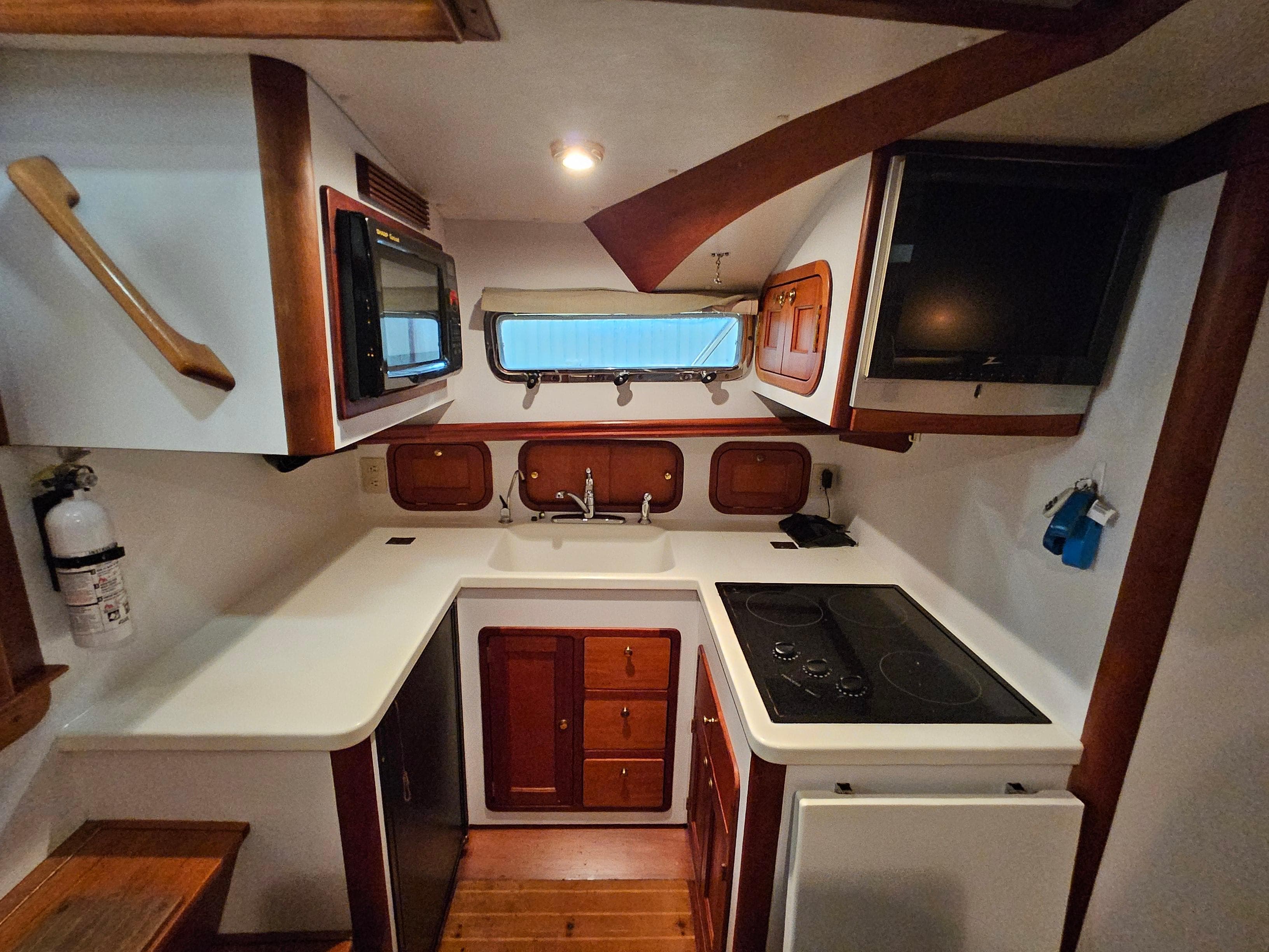 2003 Legacy 40 Hardtop Express yacht kitchen with stove, sink, microwave, and wooden cabinetry.
