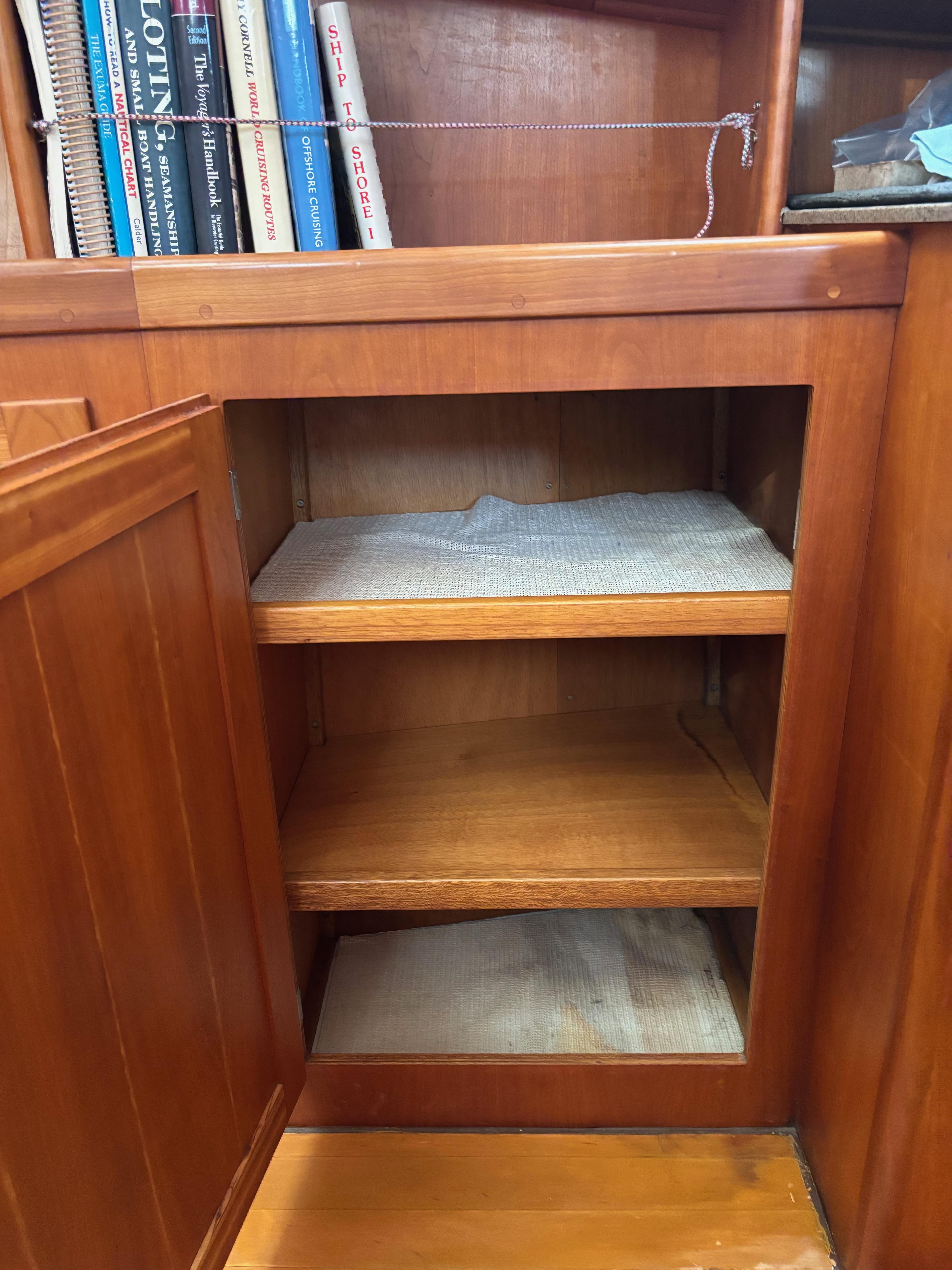 Wooden cabinet with open shelves on a 1999 Diesel Duck Trawler, books visible on top shelf.