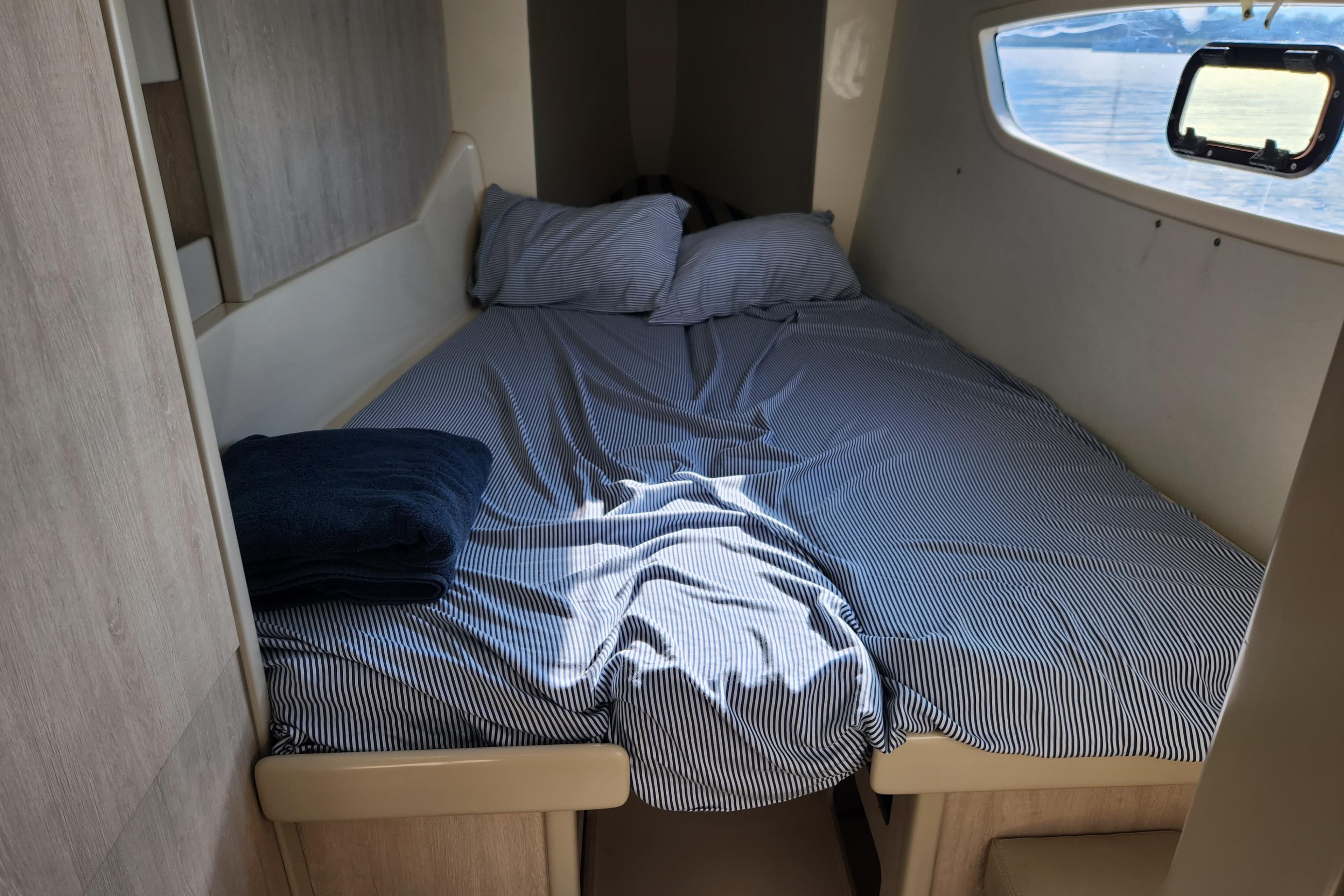Cozy cabin bed in 2015 Leopard 44 yacht with striped bedding and window view.