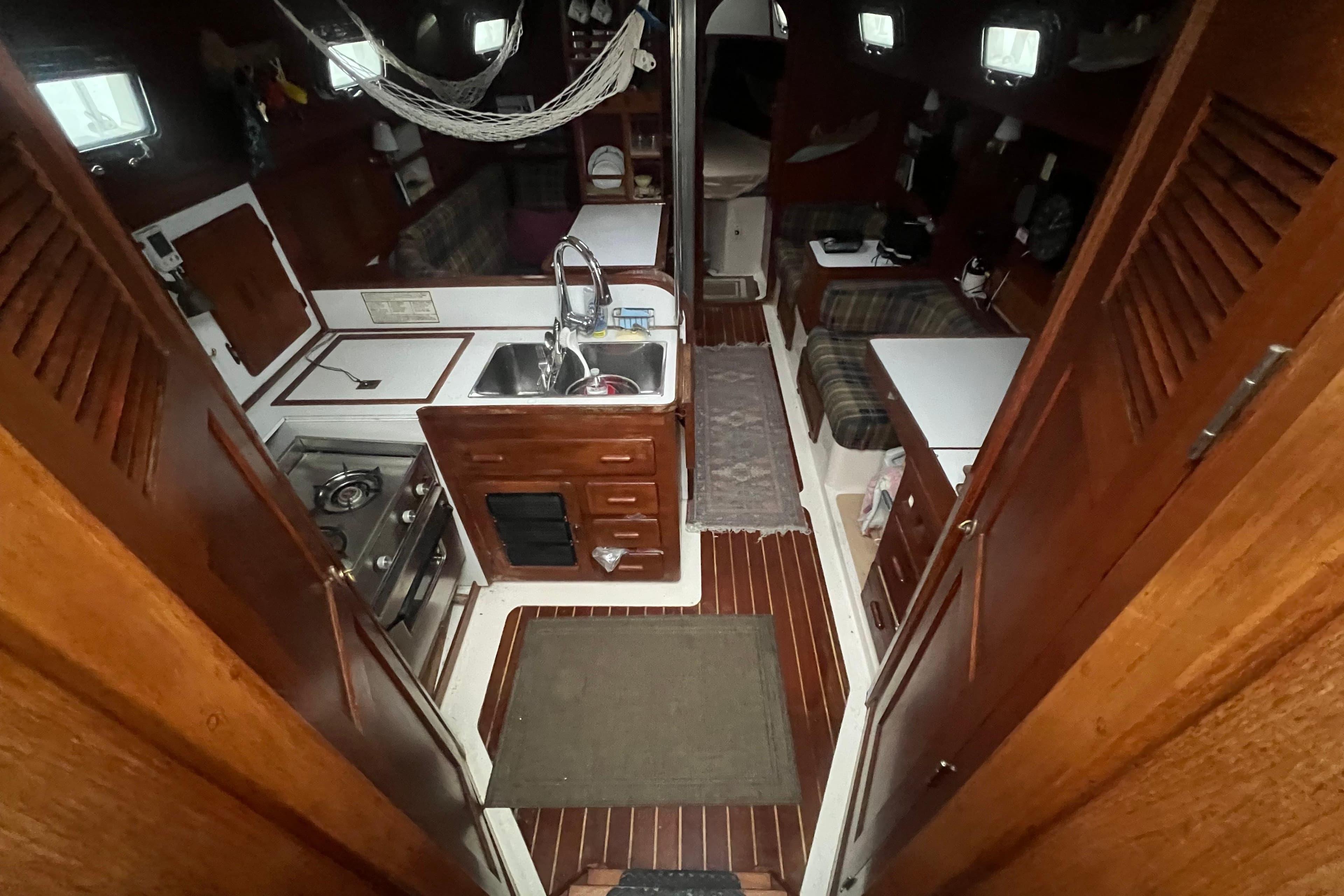 Interior of a 1993 Com-Pac Sloop sailboat with wooden cabinetry and compact kitchen.