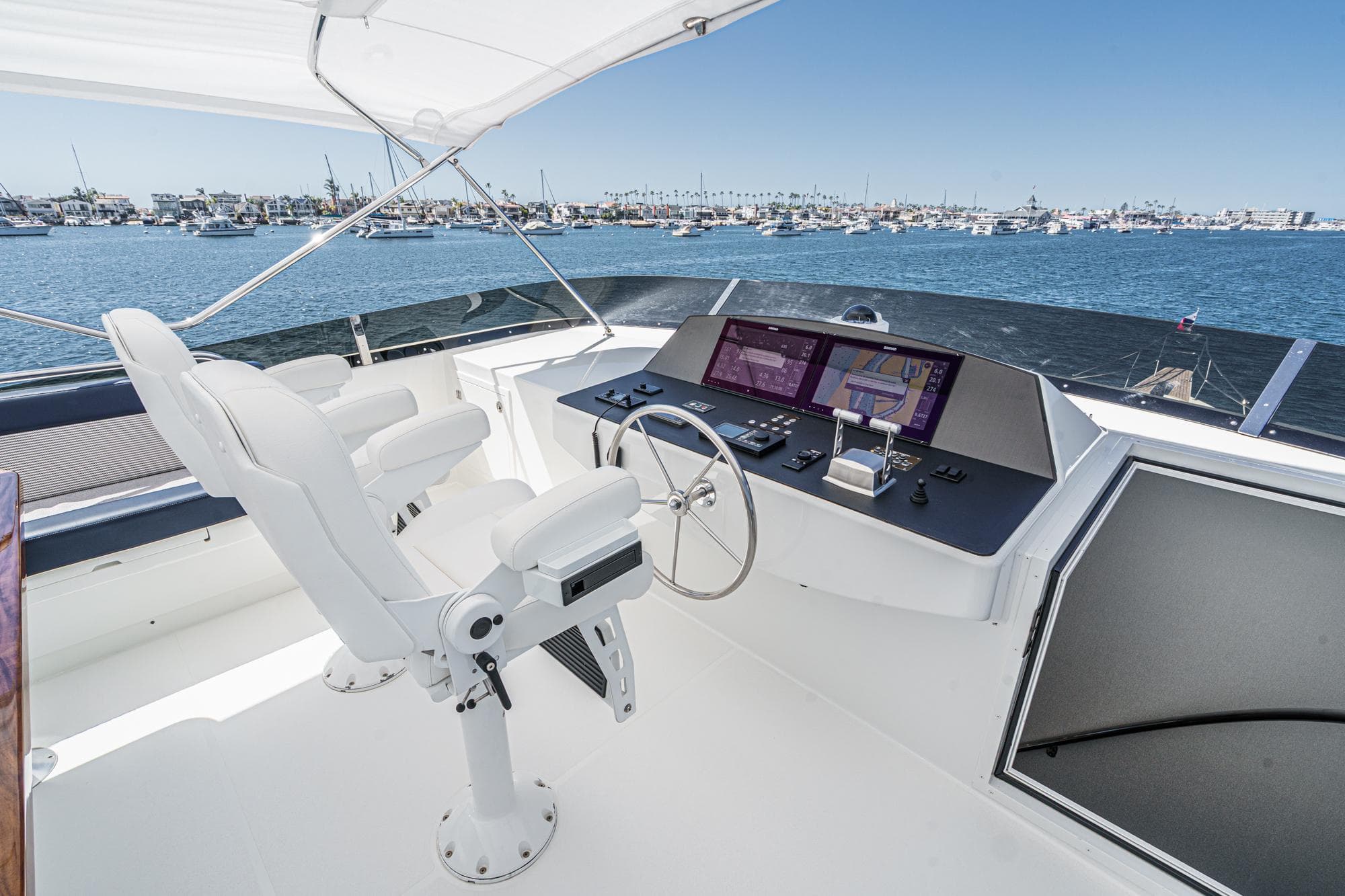 Raised pilothouse of Northcoast Yachts, 1999 model, overlooking marina with clear blue skies.