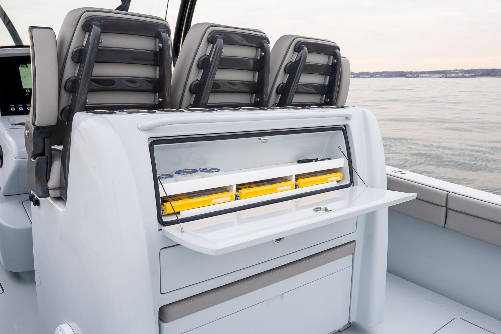 2023 Valhalla Boatworks V-33 interior with storage compartment and seating on calm water.