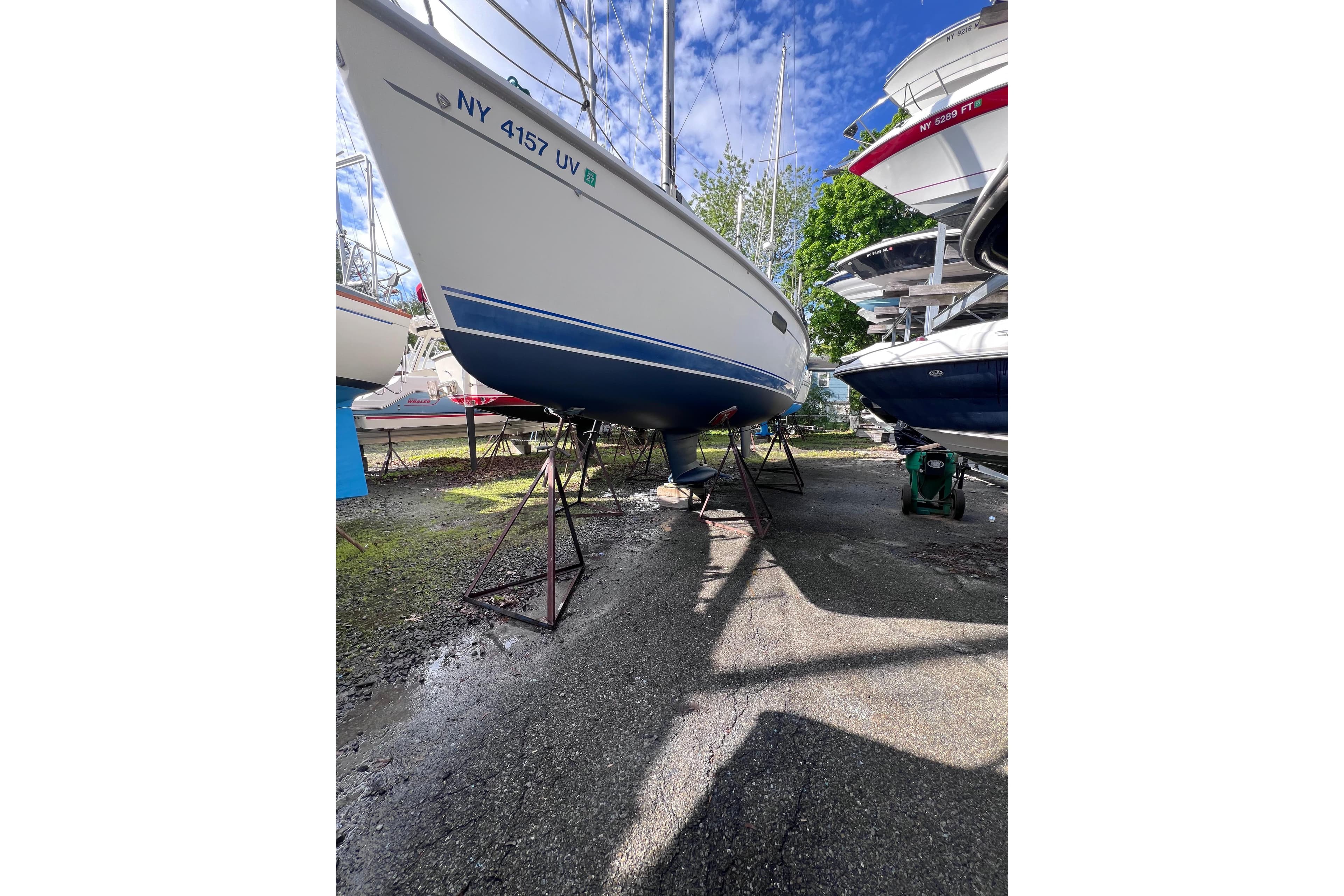 Sailboat Hunter 340, 2001 model, on stands in a boatyard under a blue sky.