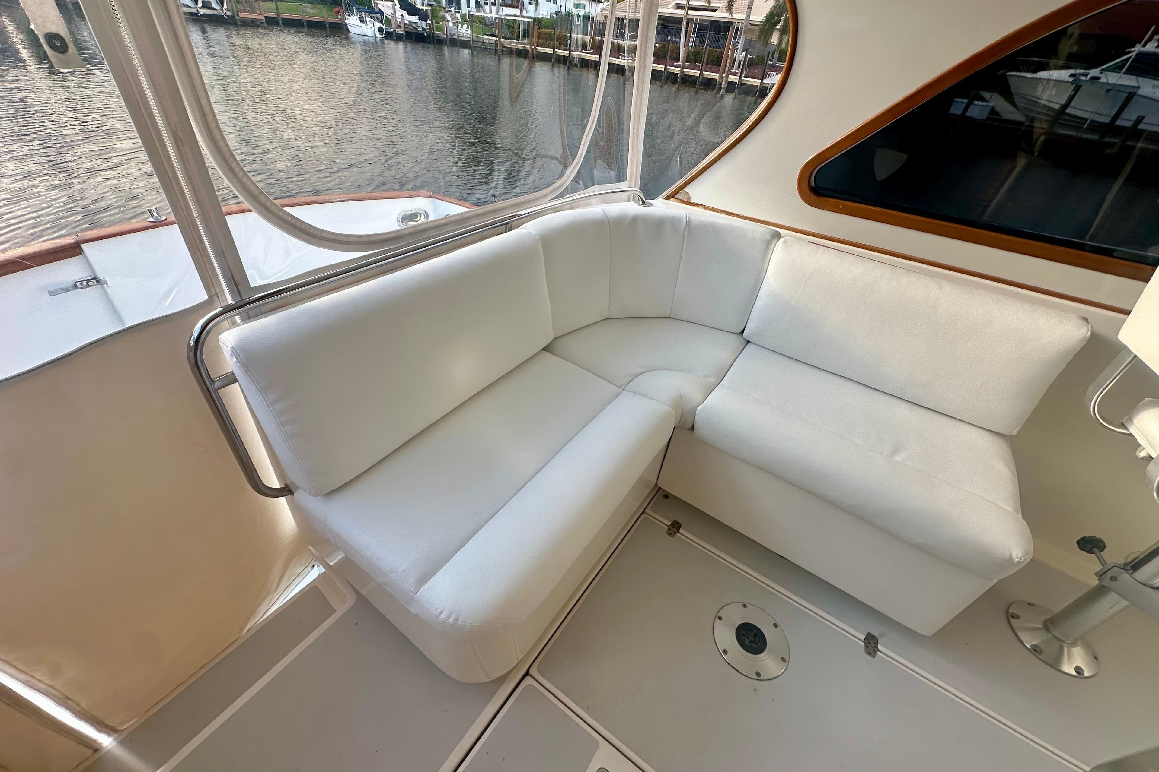 White cushioned seating area on 2005 Legacy Yachts 34 Express, overlooking marina.