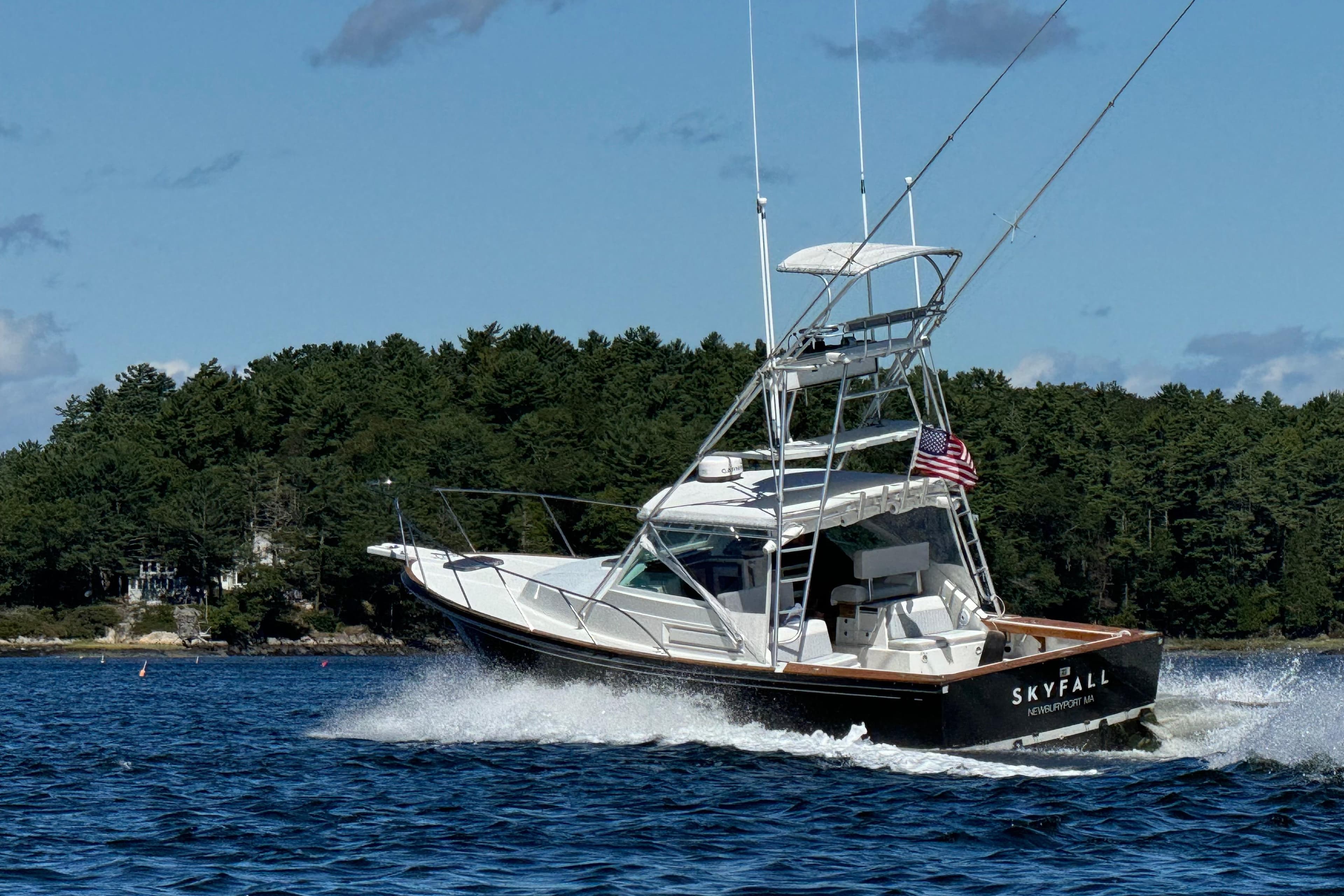 1993 Black Watch 33 boat cruising on a lake with forested shoreline.