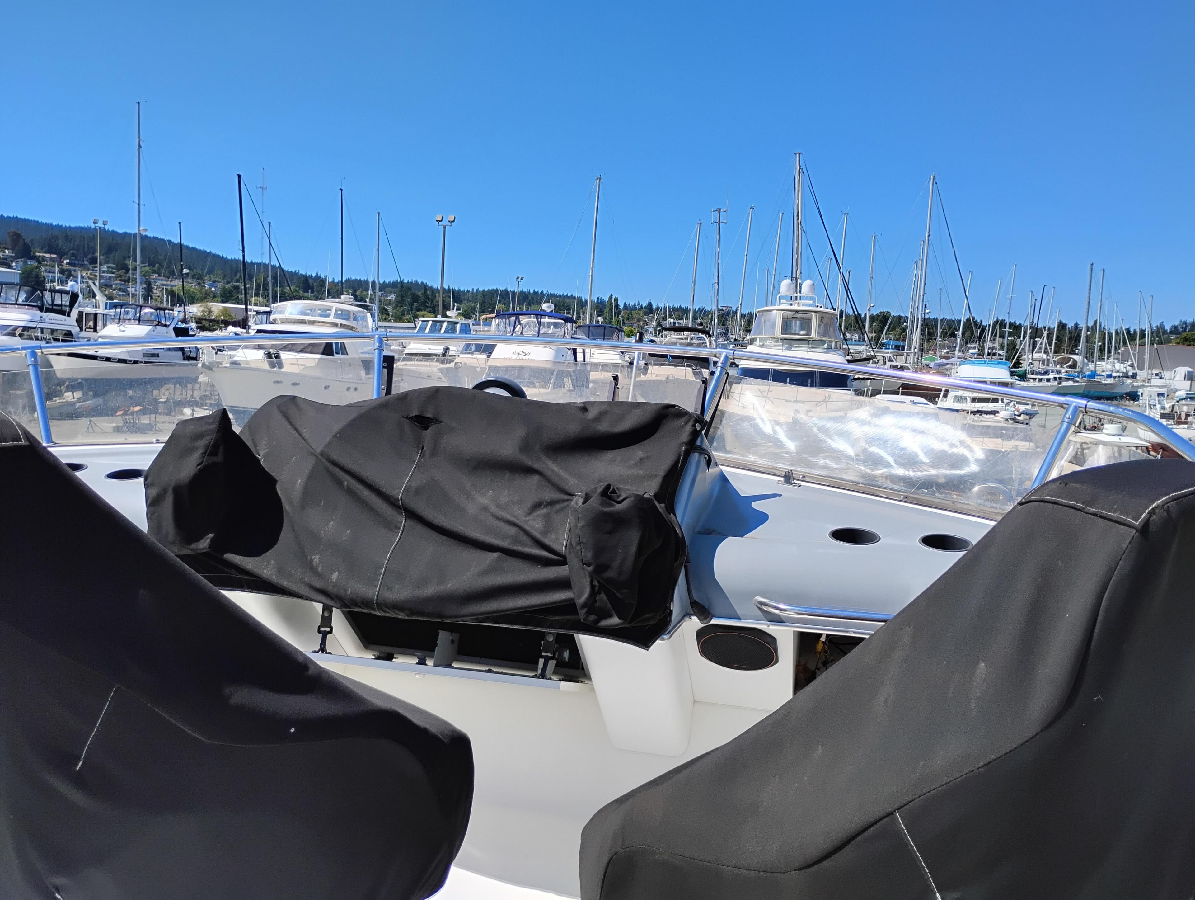 1992 Bayliner 4388 Motoryacht at marina, covered seats, clear blue sky, sailboats in background.