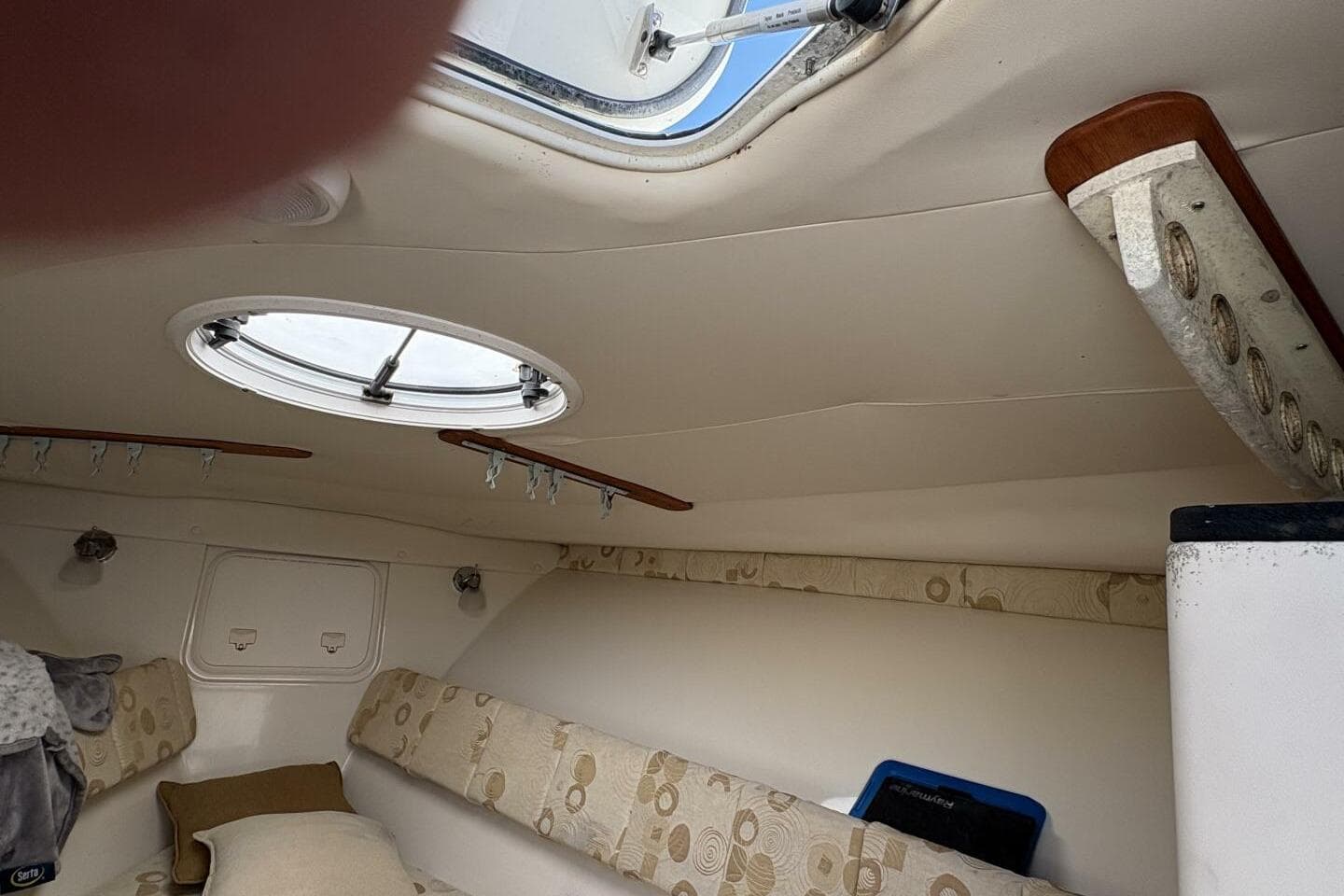 Interior cabin of 2008 Wellcraft 35 Scarab Sport boat with circular window and seating.