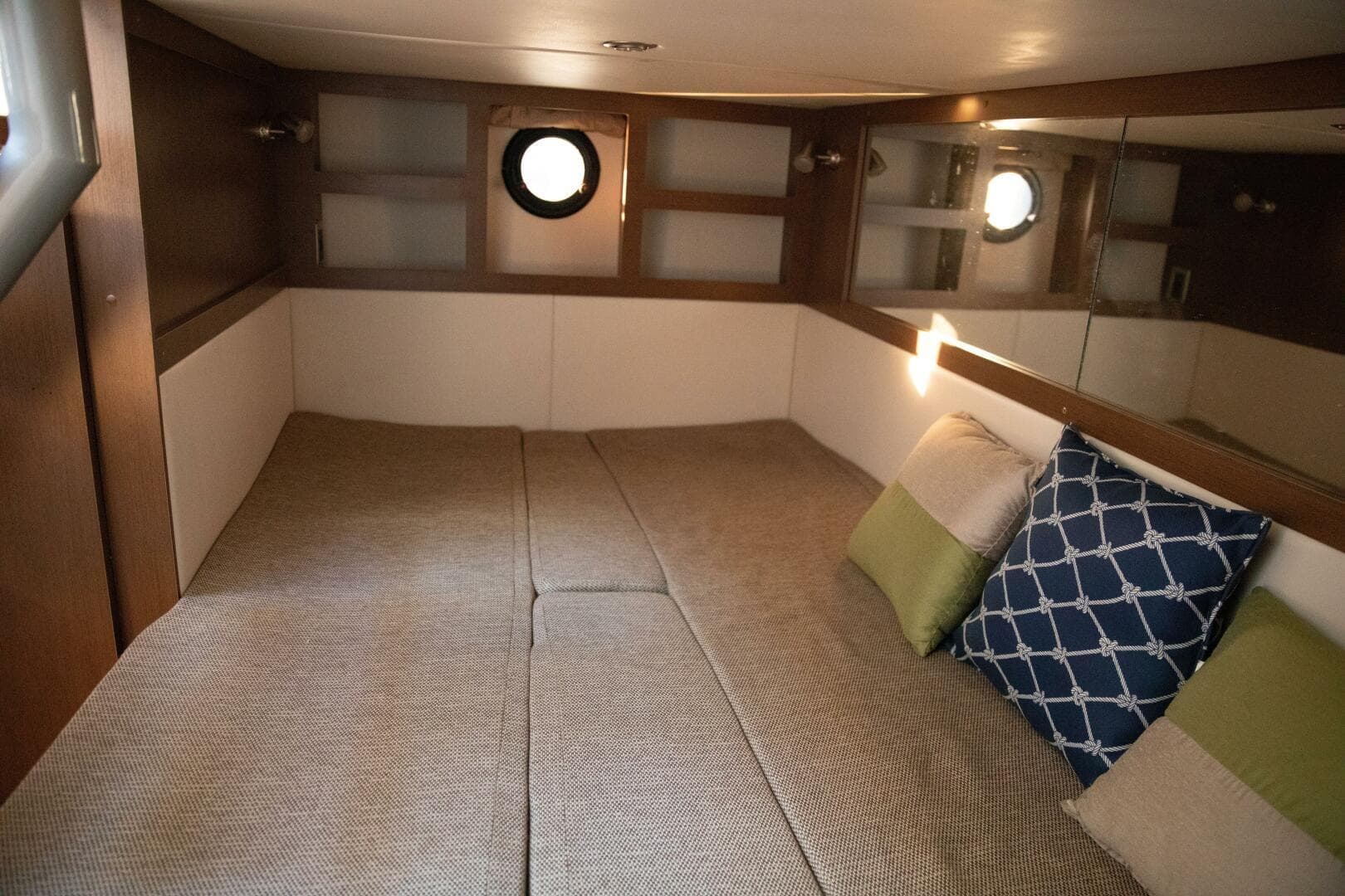 Cozy cabin interior of 2016 Sea Ray 350 Sundancer with cushions and porthole.