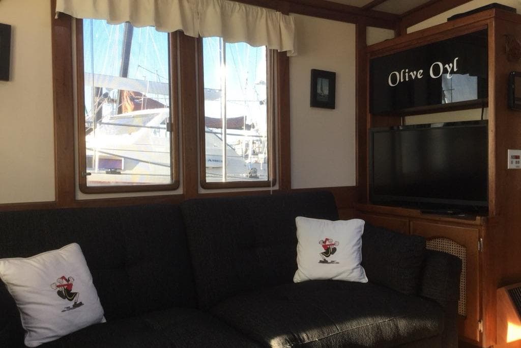 Interior of 1985 Gozzard PILGRIM boat with sofa, TV, and nautical decor.