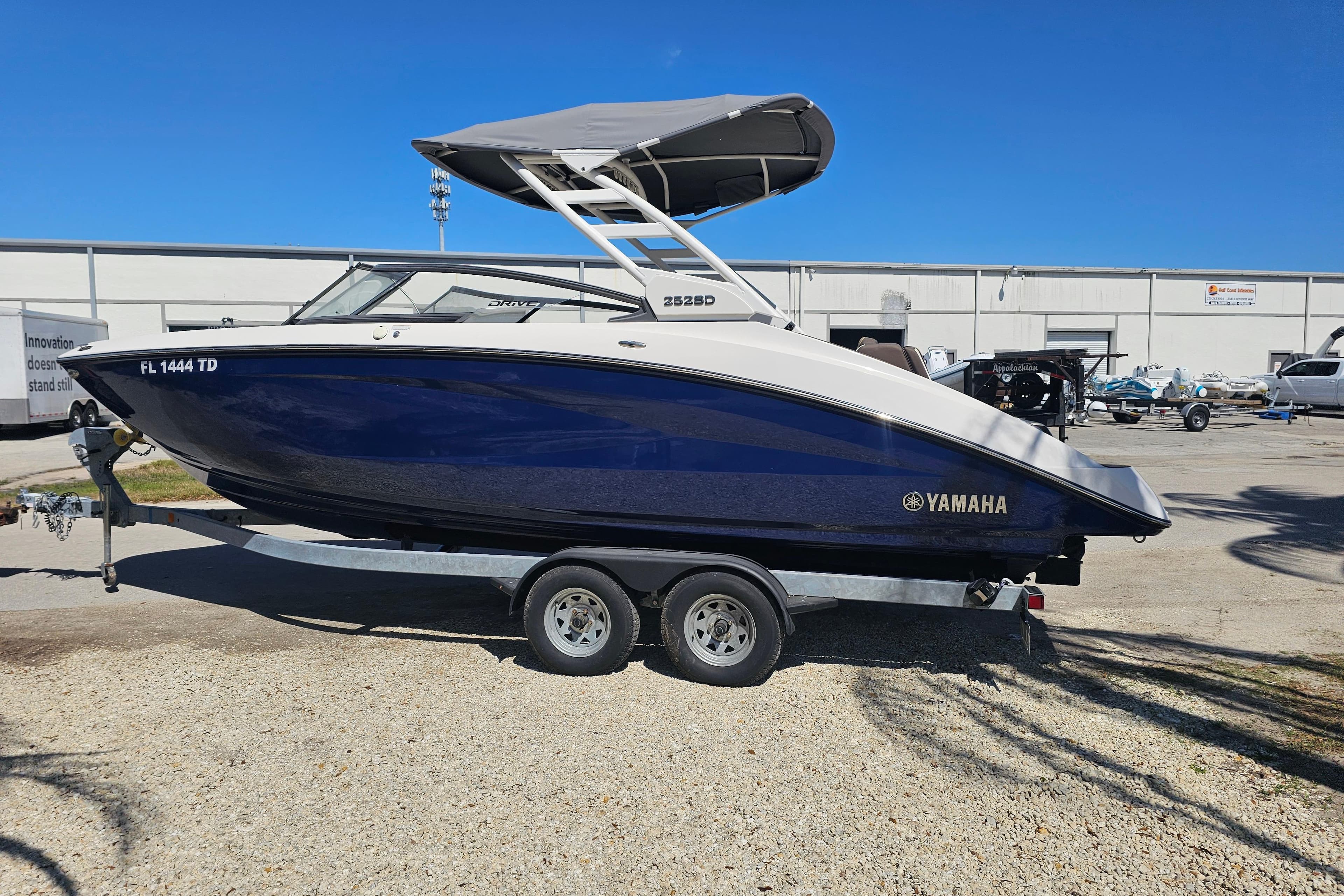 2022 Yamaha Boats 252SD on trailer, blue and white, parked outdoors.