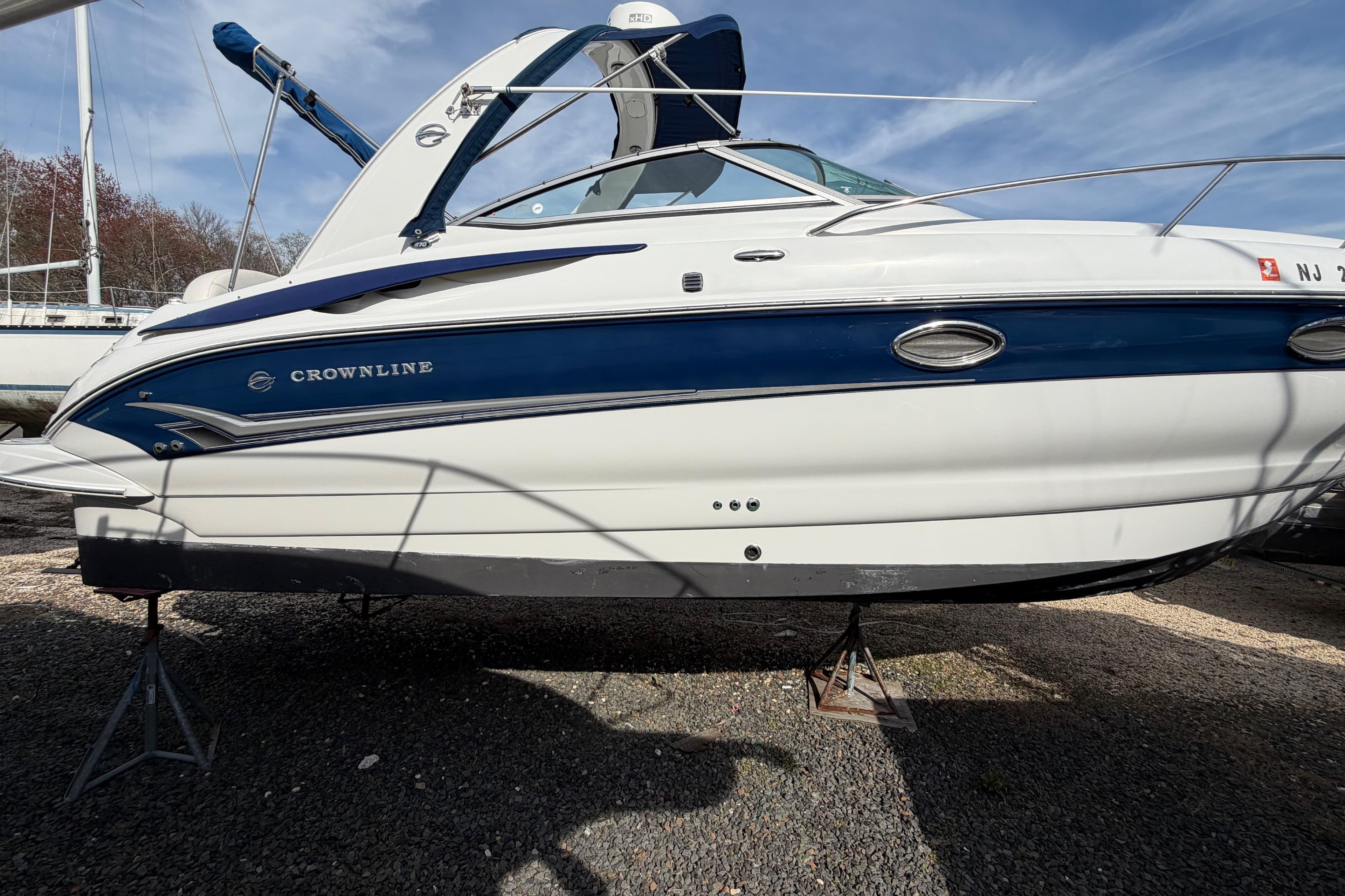 2006 Crownline 270 CR boat on stands, blue and white exterior, sunny day.