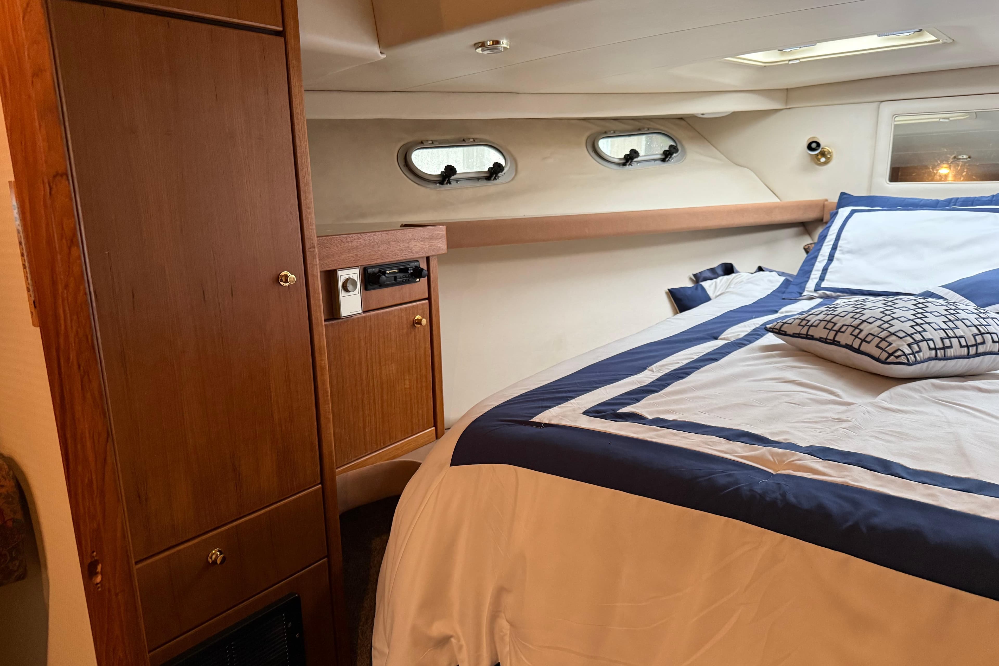 Interior of 1997 Bayliner 47 Motoryacht bedroom with wood cabinetry and nautical bedding.
