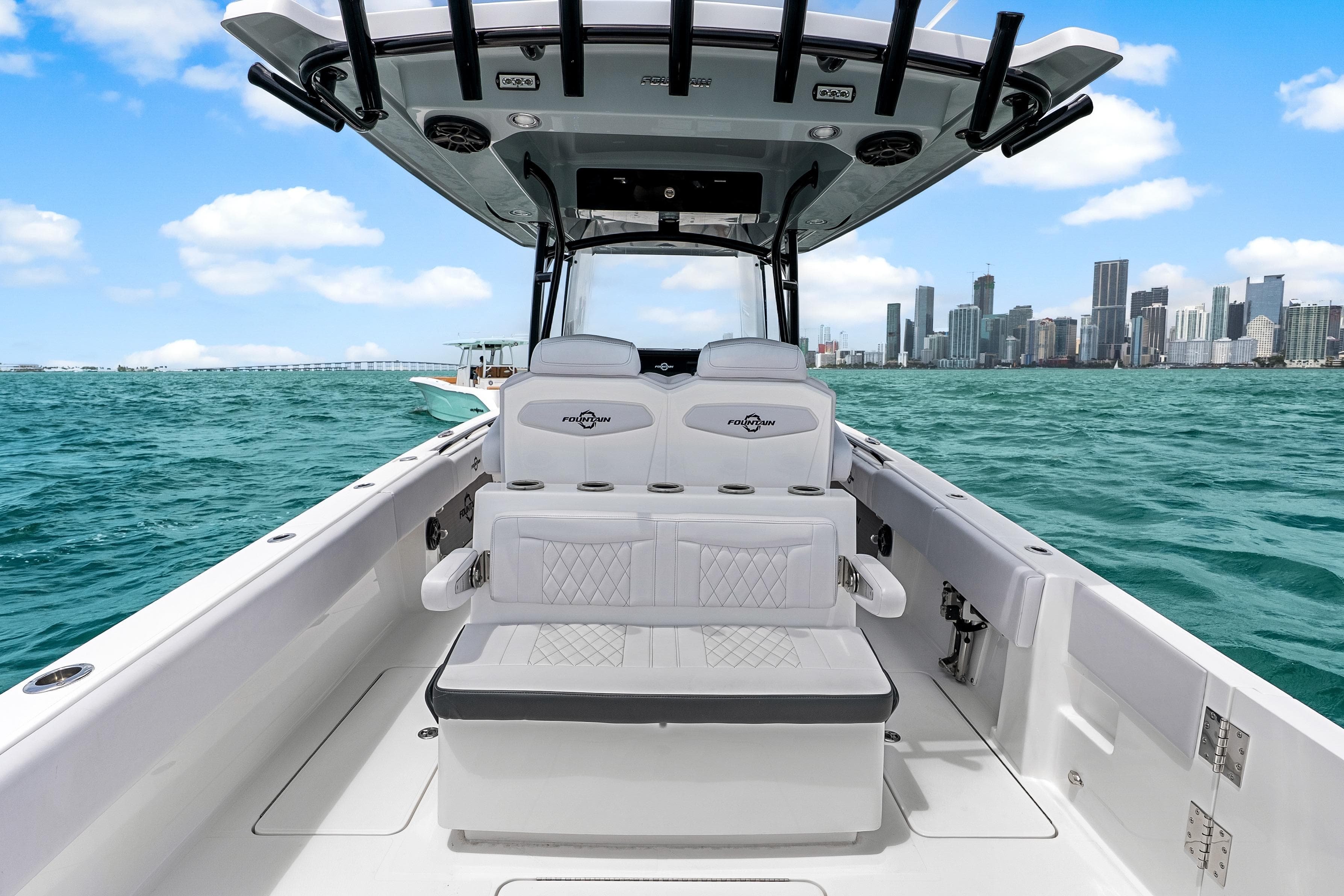 2025 Fountain 34 Center Console boat on turquoise water with city skyline backdrop.