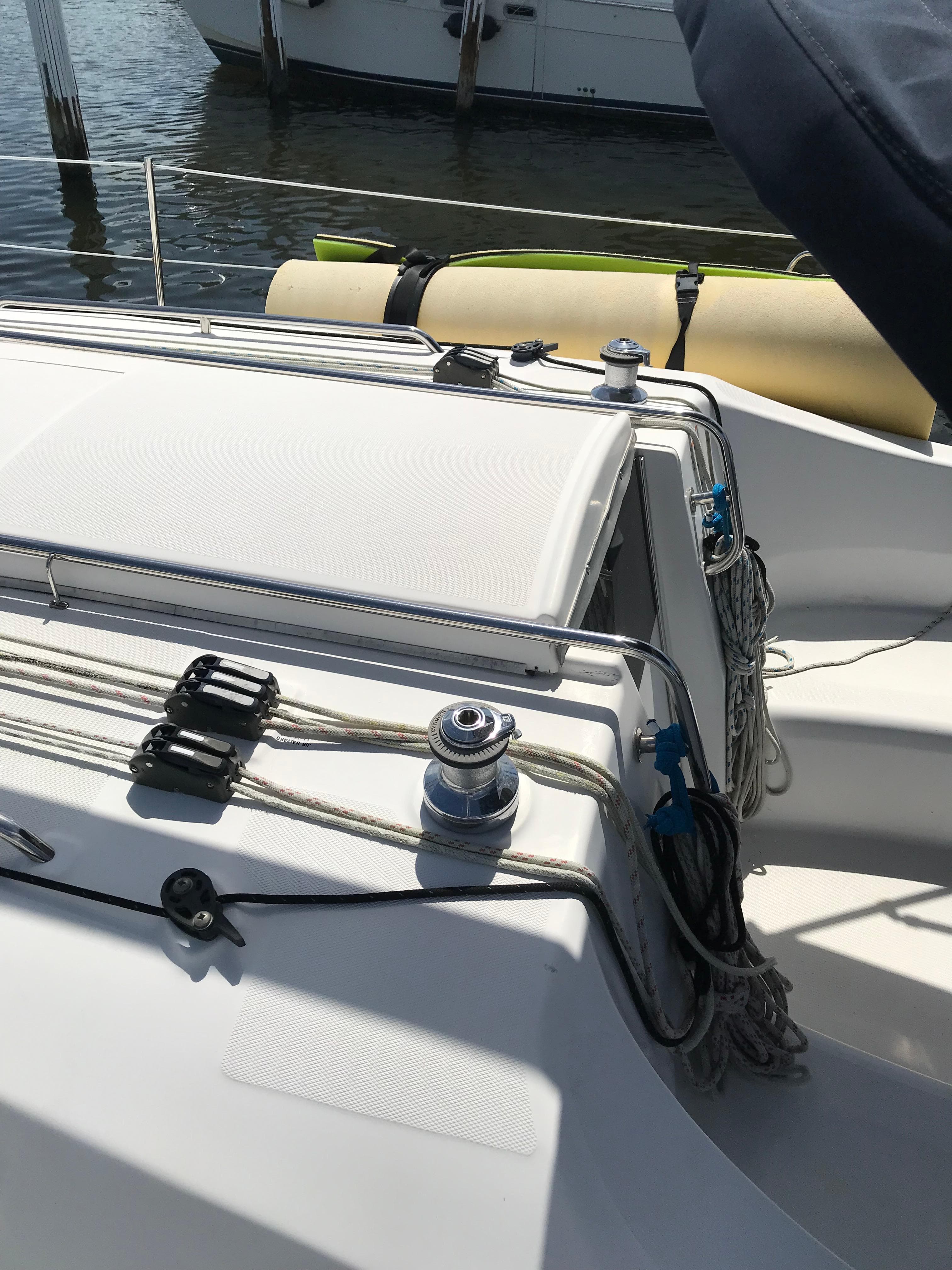 2009 Hunter 310 sailboat deck with winches and ropes in a marina setting.