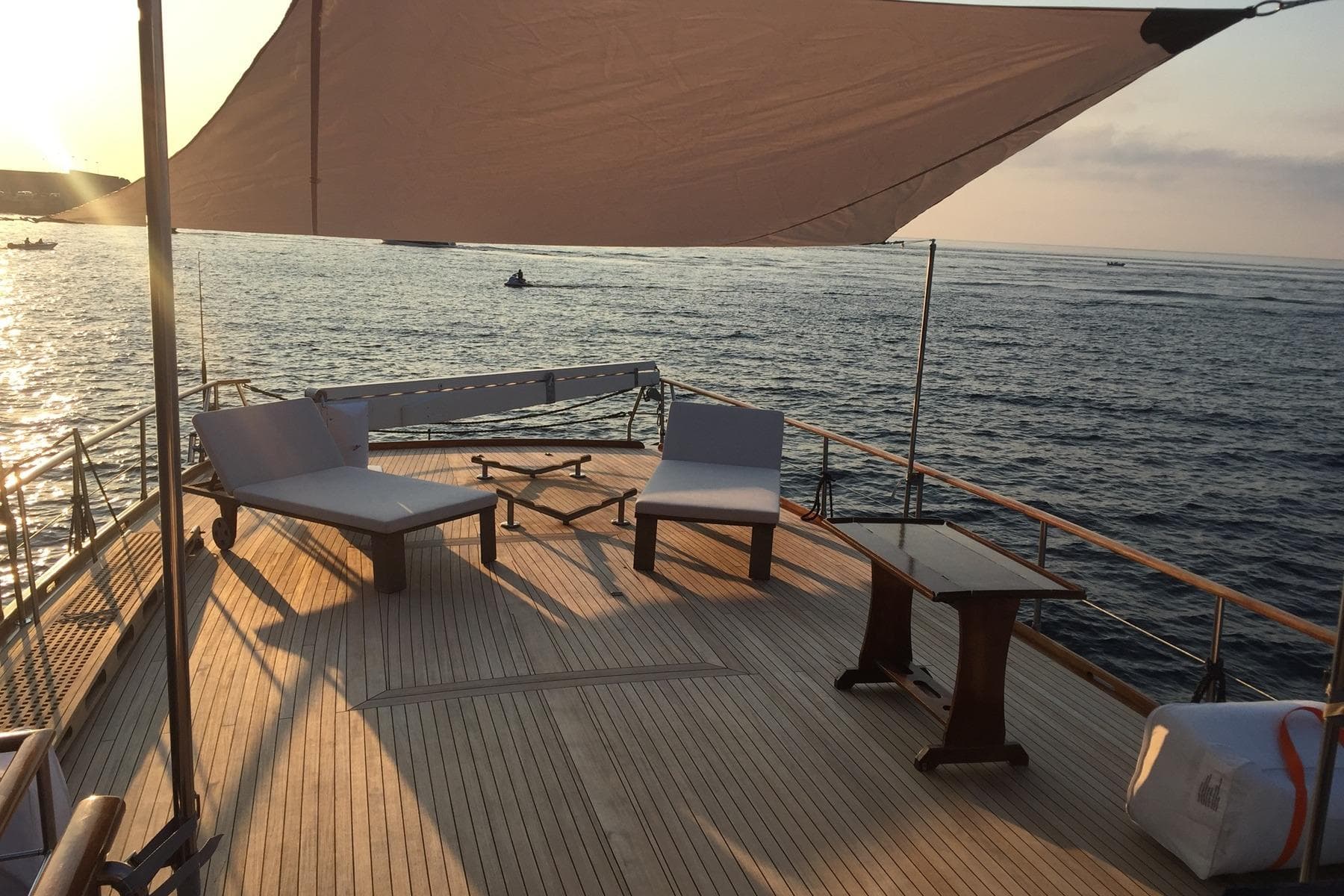 Luxurious deck of 1935 Peschereccio Diporto 20 yacht at sunset, featuring elegant seating.