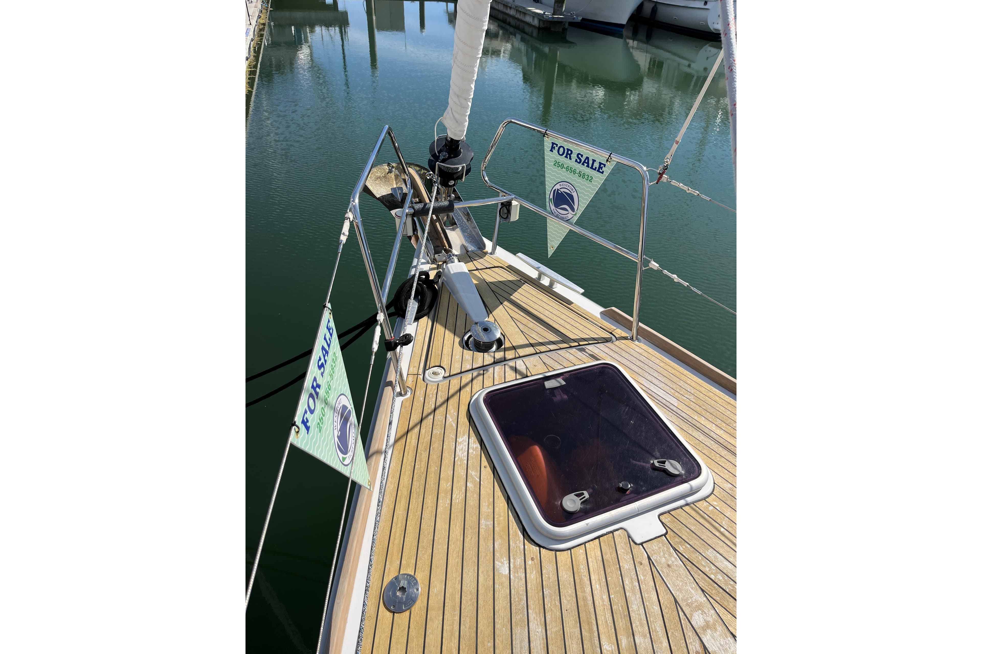 2014 Beneteau Oceanis 45 sailboat deck with "For Sale" signs at marina.