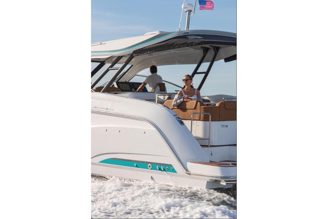 2026 Jeanneau TH38 yacht cruising with passengers, American flag waving.