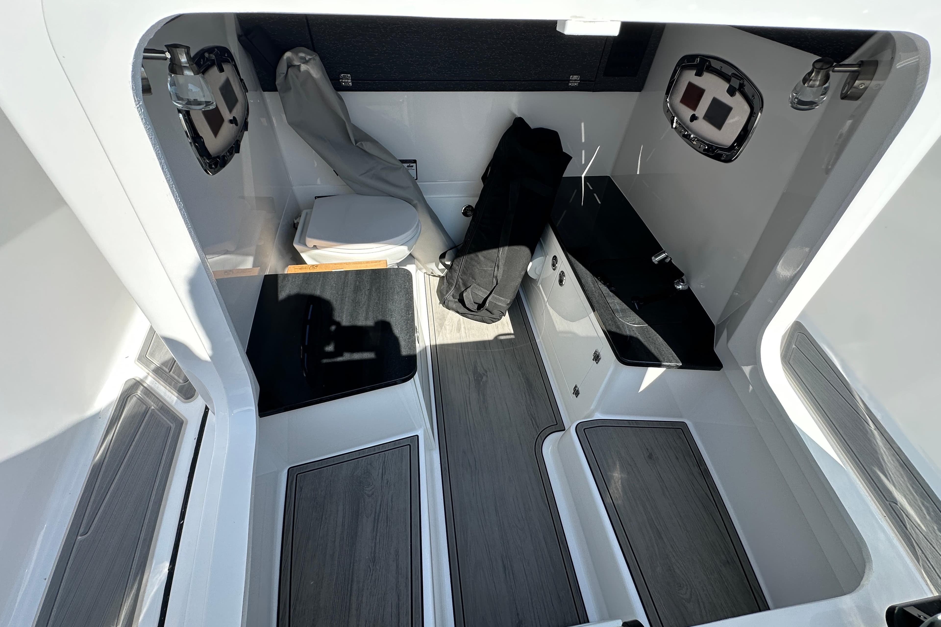 Interior of 2026 Monterey Elite 25 OB boat with toilet and storage area.