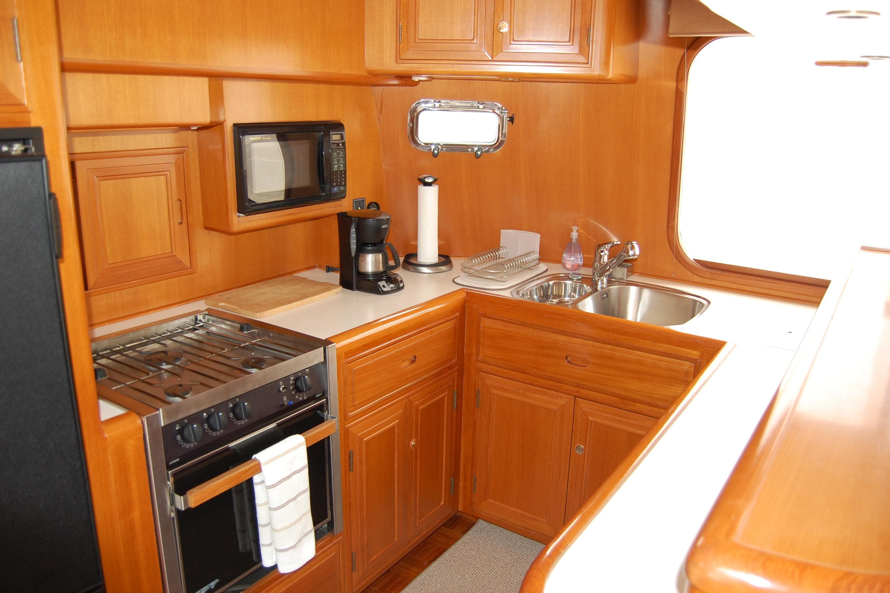 2001 Ocean Alexander Classico yacht kitchen with wood cabinetry, stove, microwave, and sink.