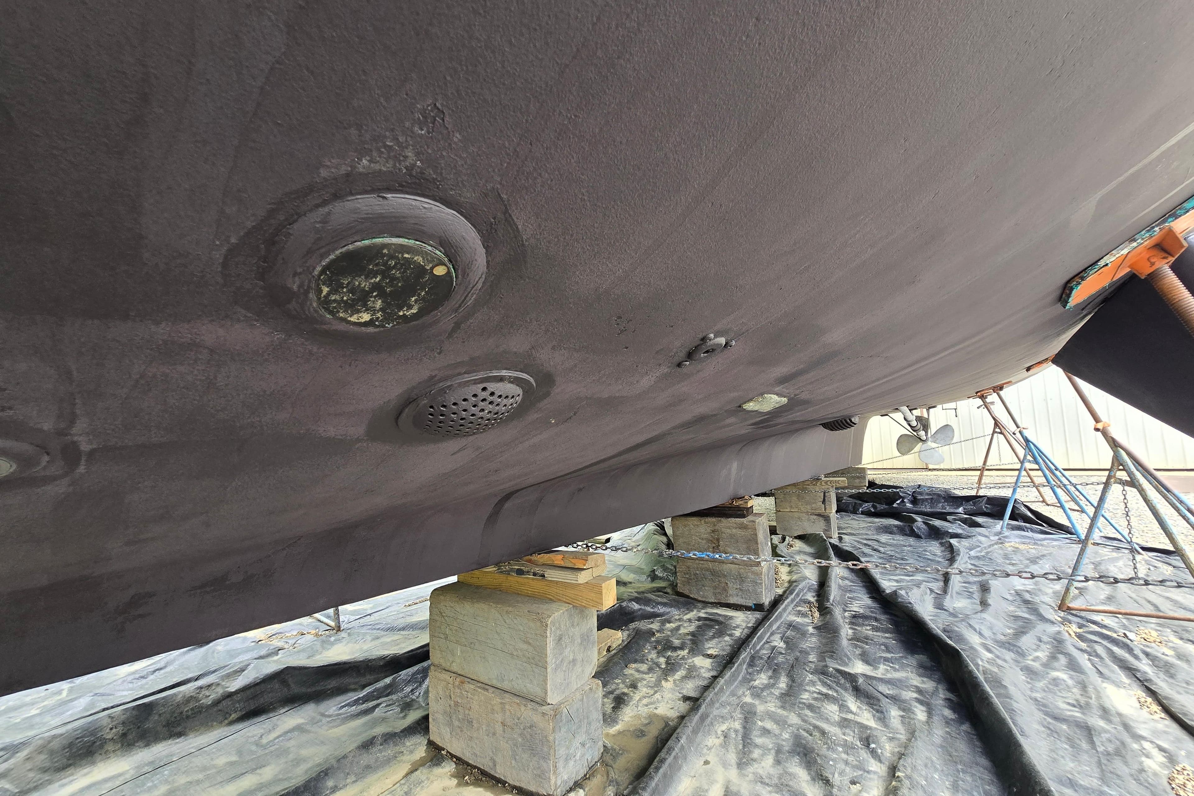 Underside of 1980 Hatteras 70 Motor Yacht on blocks, showing hull details.