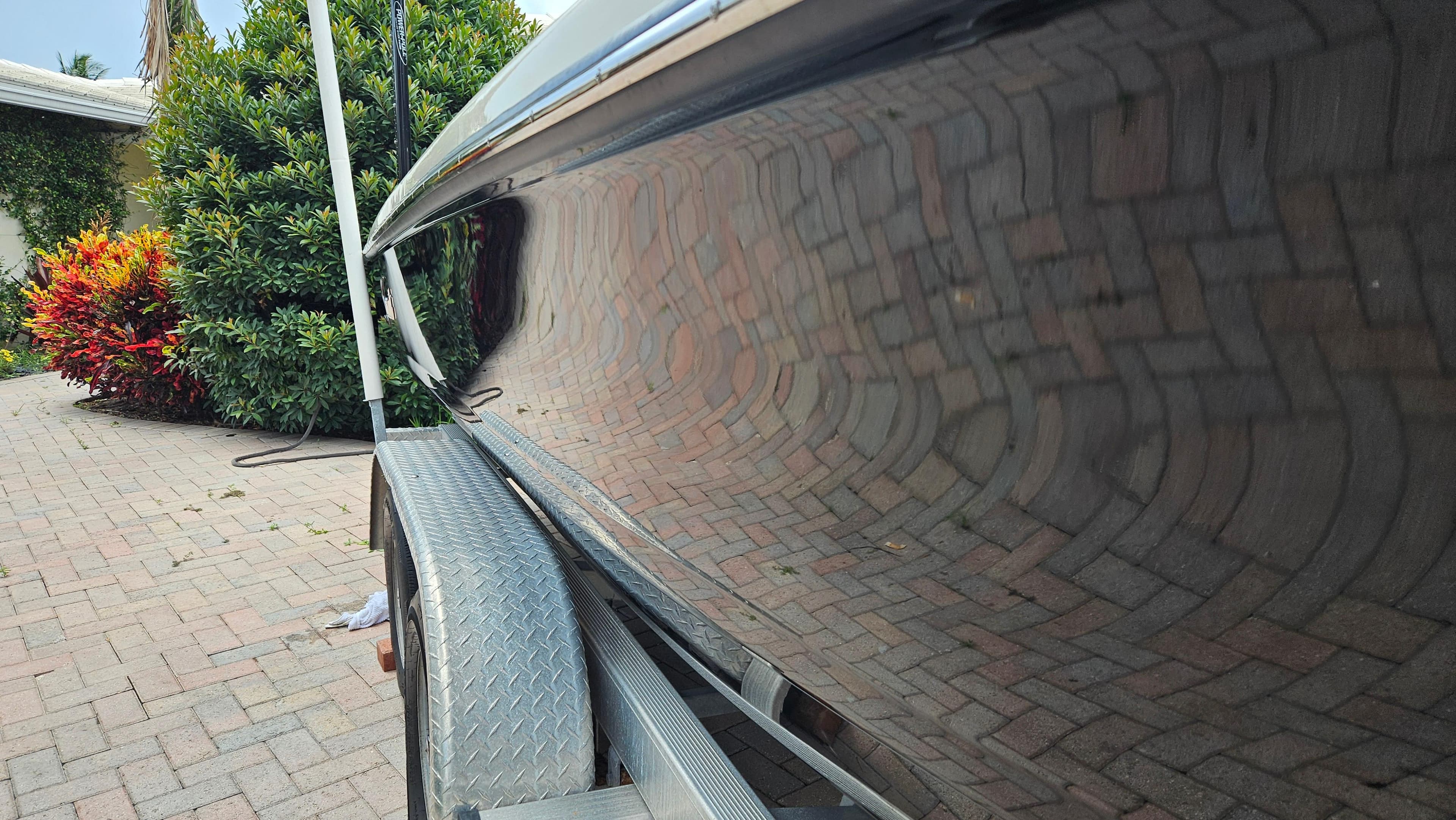 2021 Scout 231 XS boat on trailer, reflecting brick pavement and lush greenery.