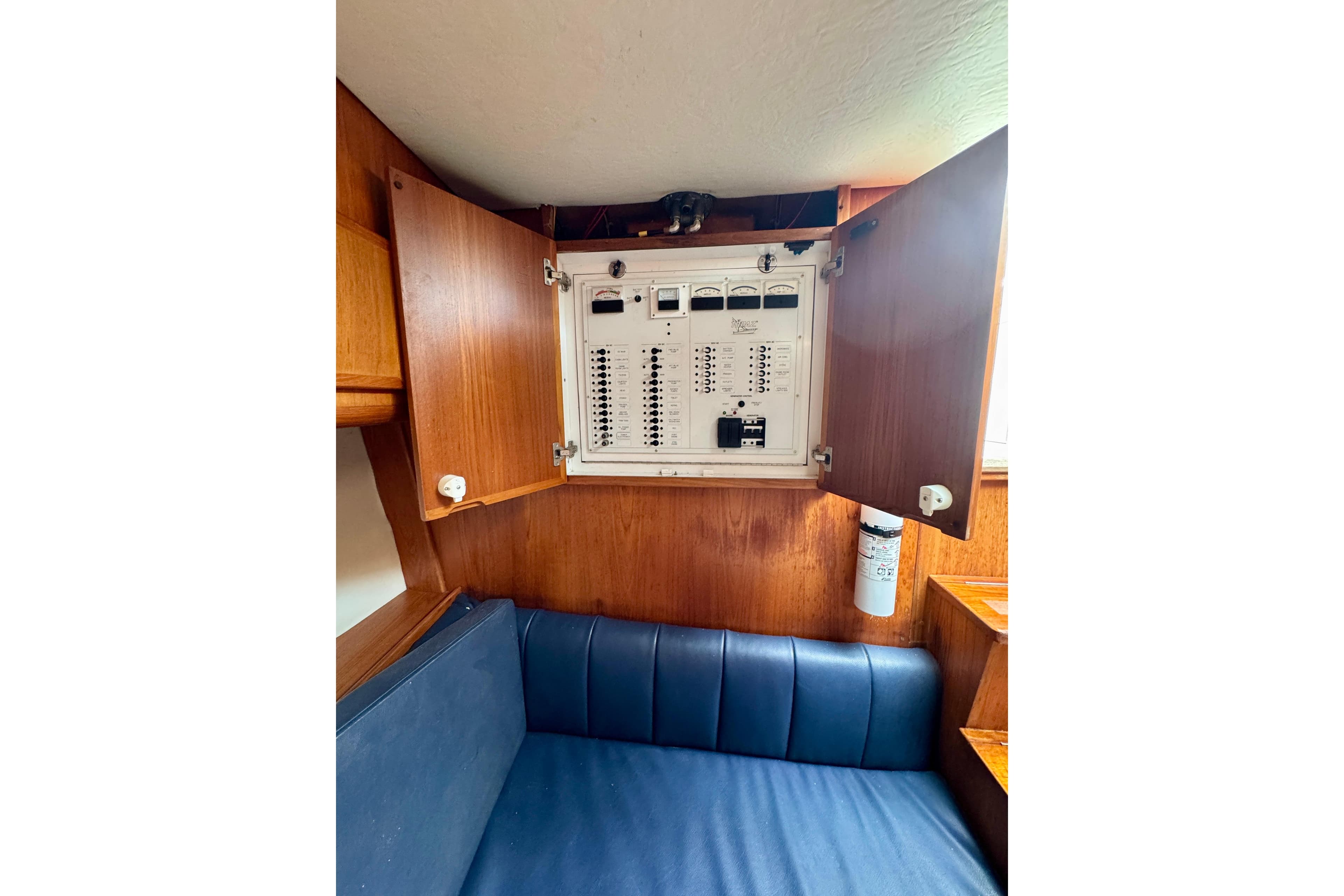 Electrical panel inside 2004 Topaz 32 Express boat with wooden cabinetry and blue seating.