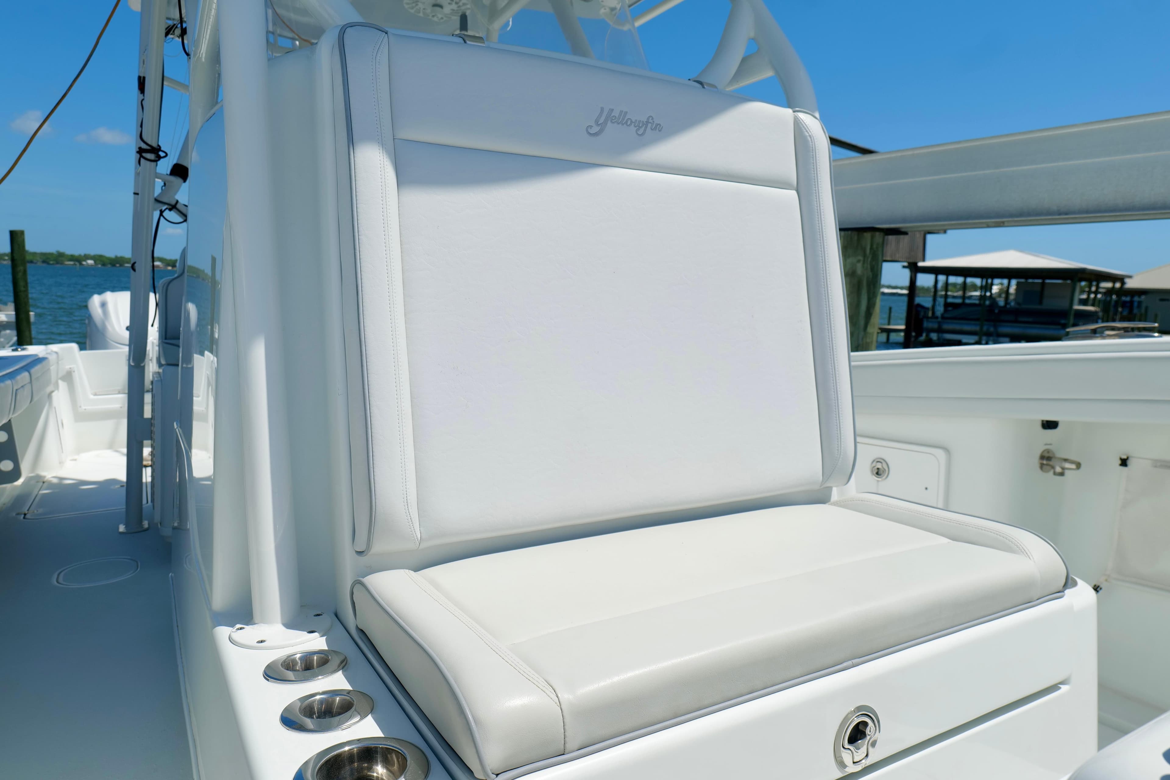 2018 Yellowfin 36 Offshore boat seat with cup holders, docked by the water.