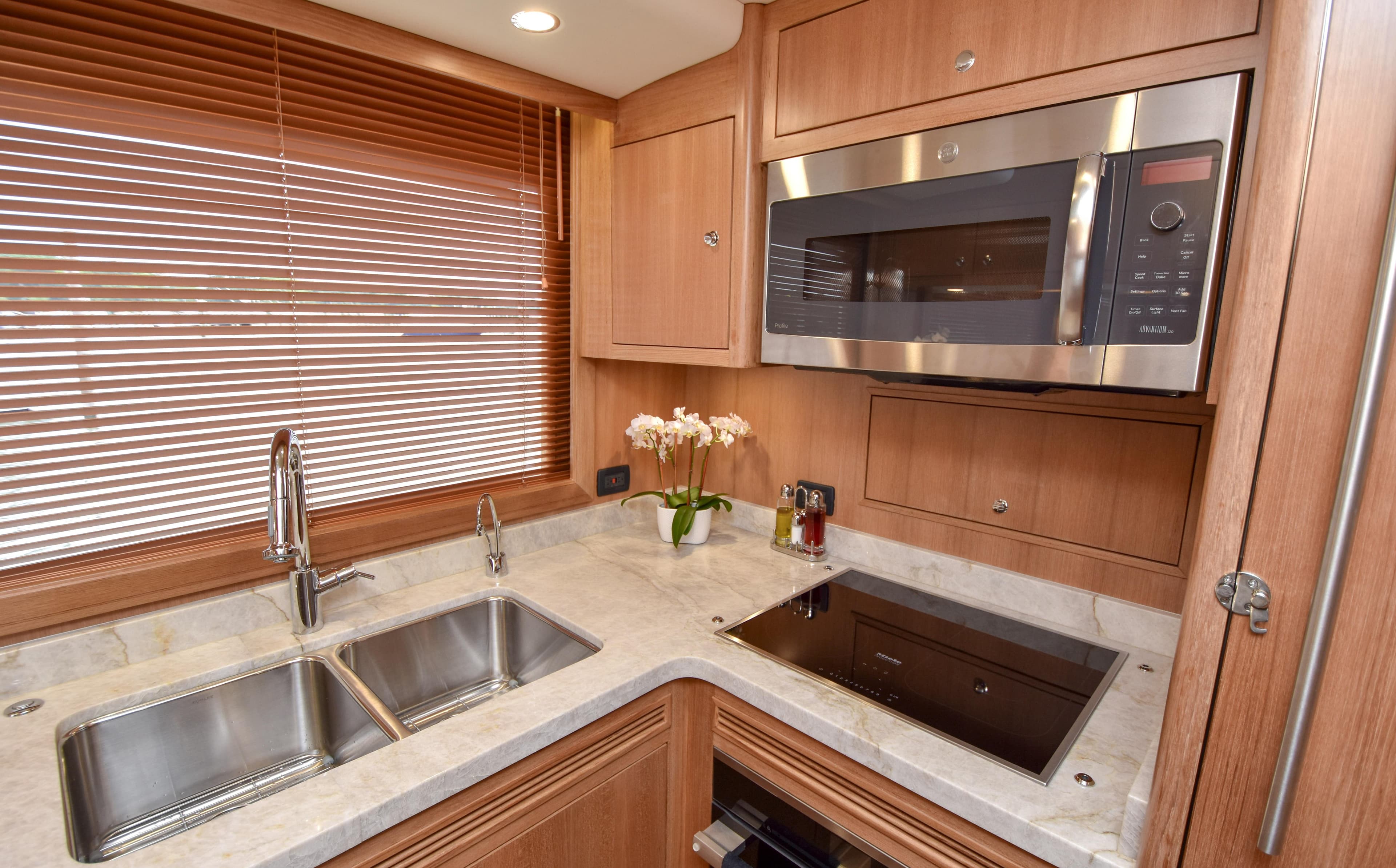 Modern kitchen in 2020 Fleming 78 yacht with stainless steel appliances and wooden cabinetry.