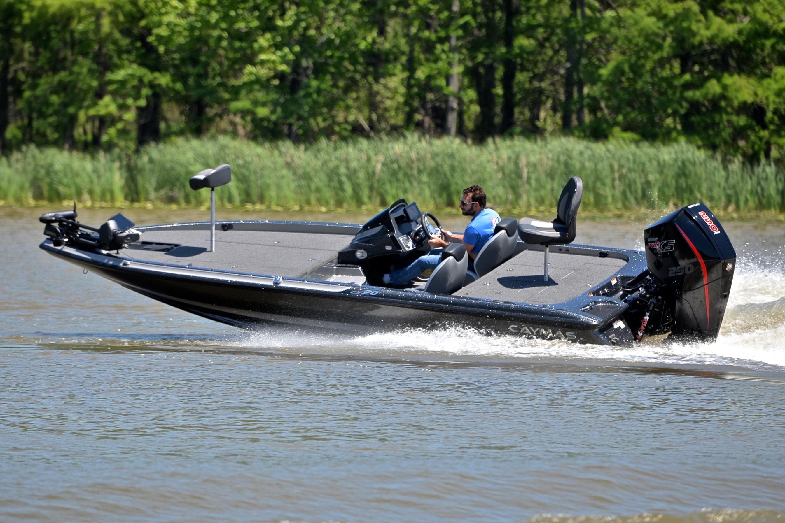2022 Caymas CX 20 boat speeding on a lake with lush green background.