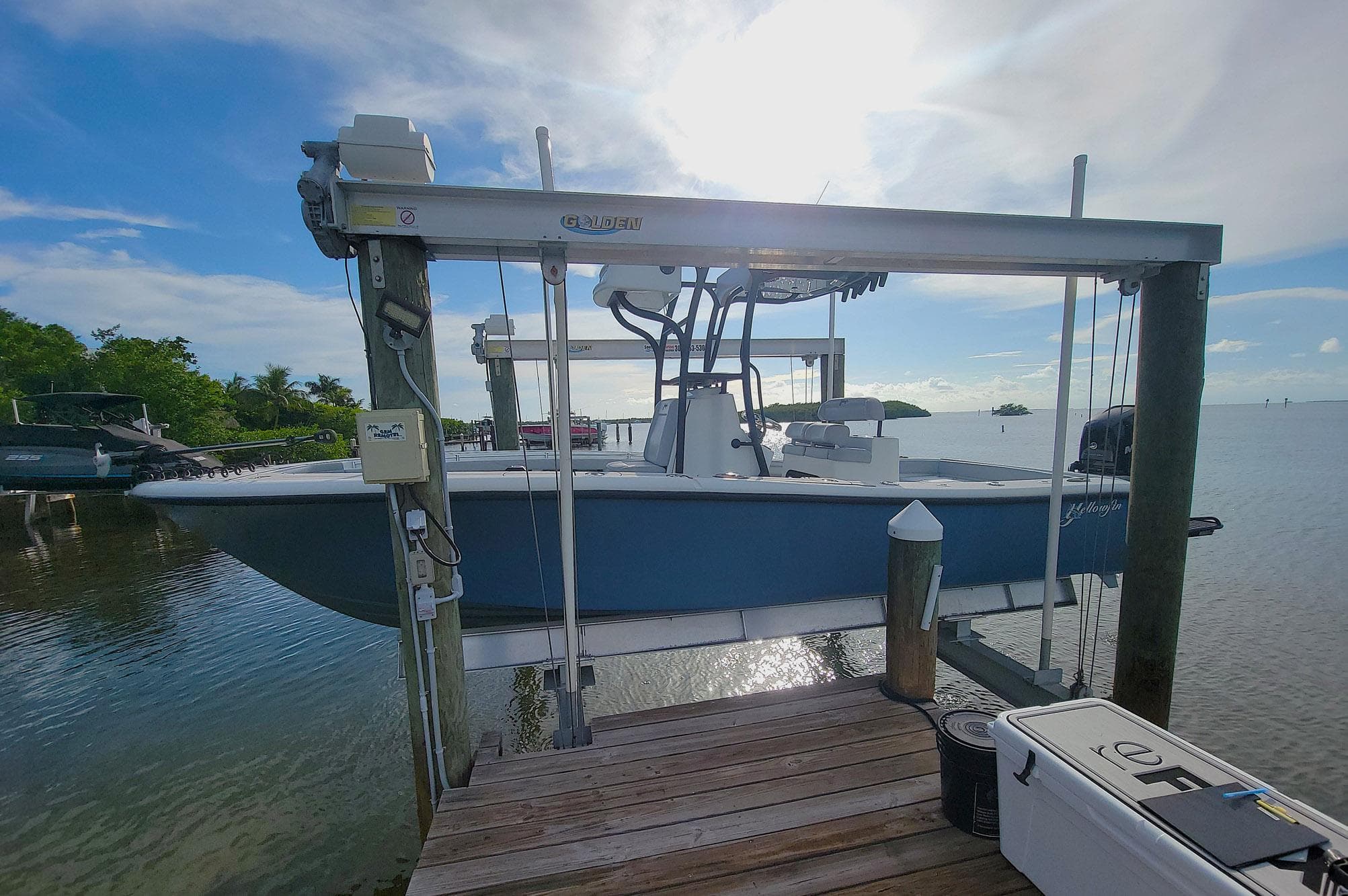 2021 Yellowfin 26 Hybrid boat on lift at sunny waterfront dock.