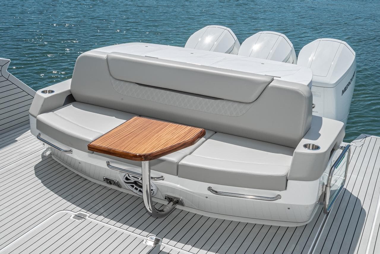 2024 Cruisers Yachts 50 GLS rear seating area with wooden table and triple outboard engines.