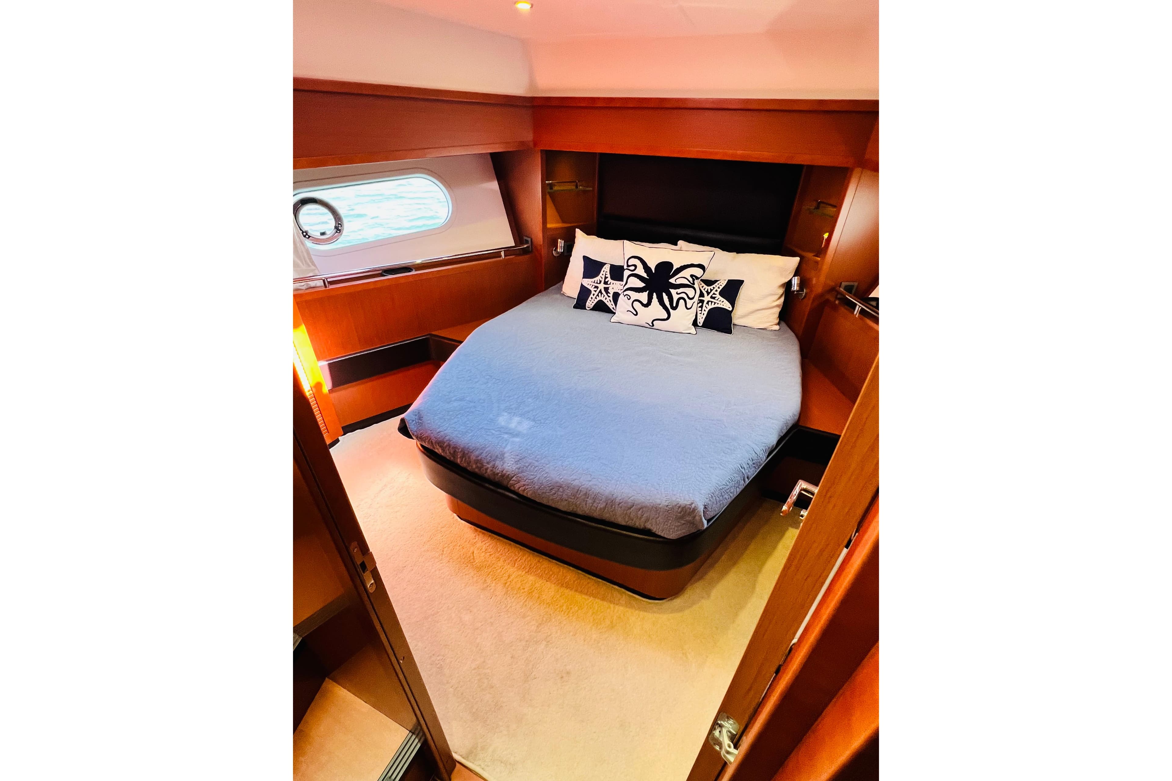Luxurious cabin interior of 2014 Beneteau Swift Trawler 50 with cozy bed and nautical decor.