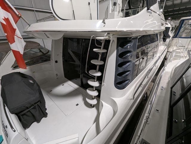 1999 Carver 530 Voyager Pilothouse yacht docked indoors with Canadian flag.